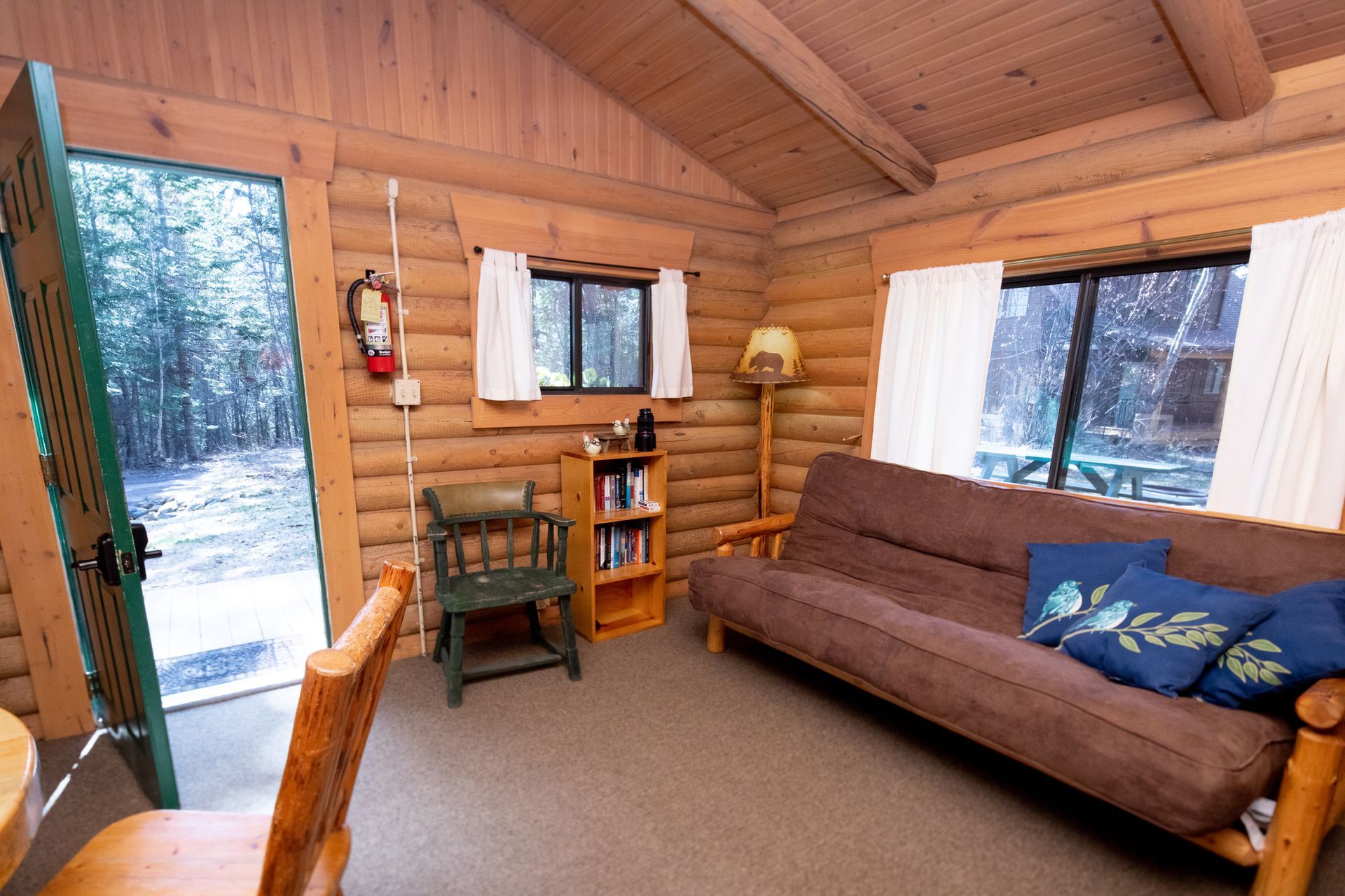A living room in a log cabin with a couch and chairs