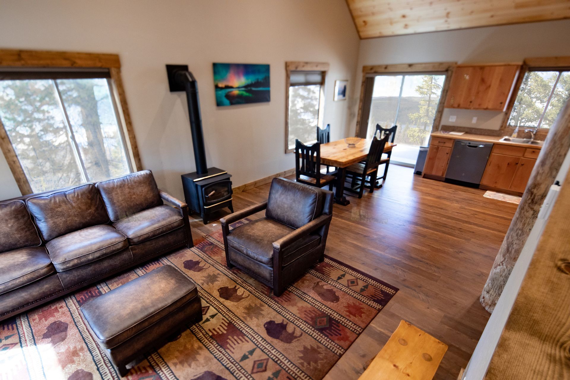 A living room with a couch , chairs , ottoman and a wood stove.