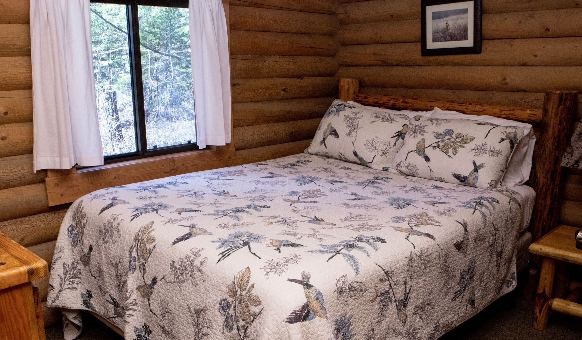 A bedroom in a log cabin with a bed and a window.