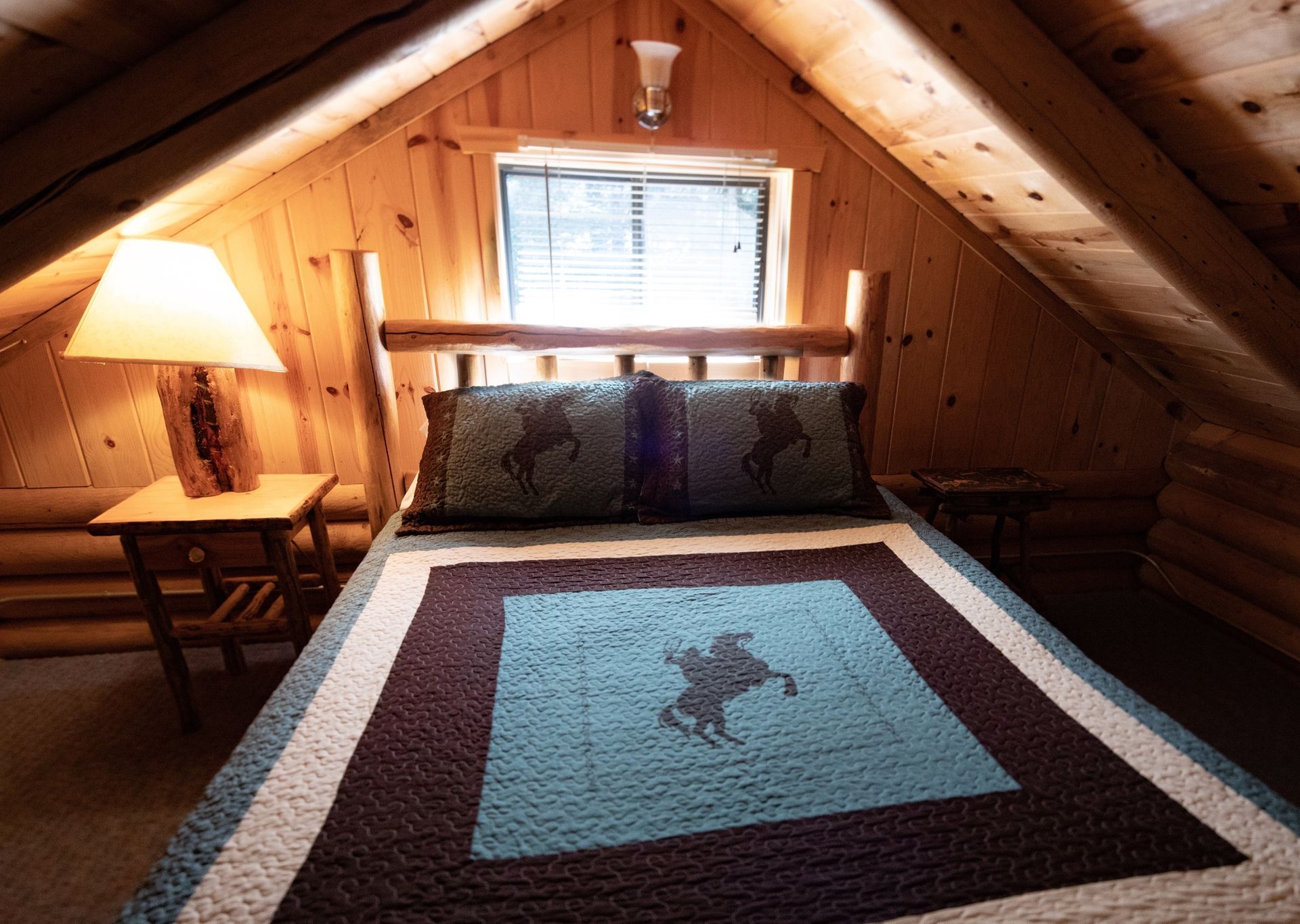 A bedroom in a log cabin with a bed and a lamp