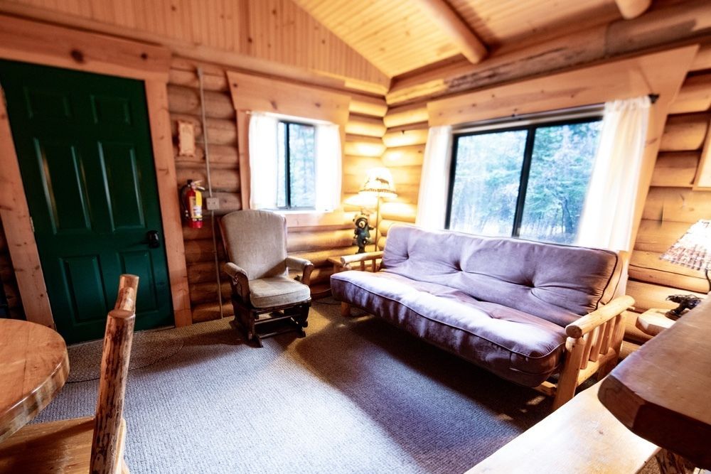A living room in a log cabin with a couch and chairs