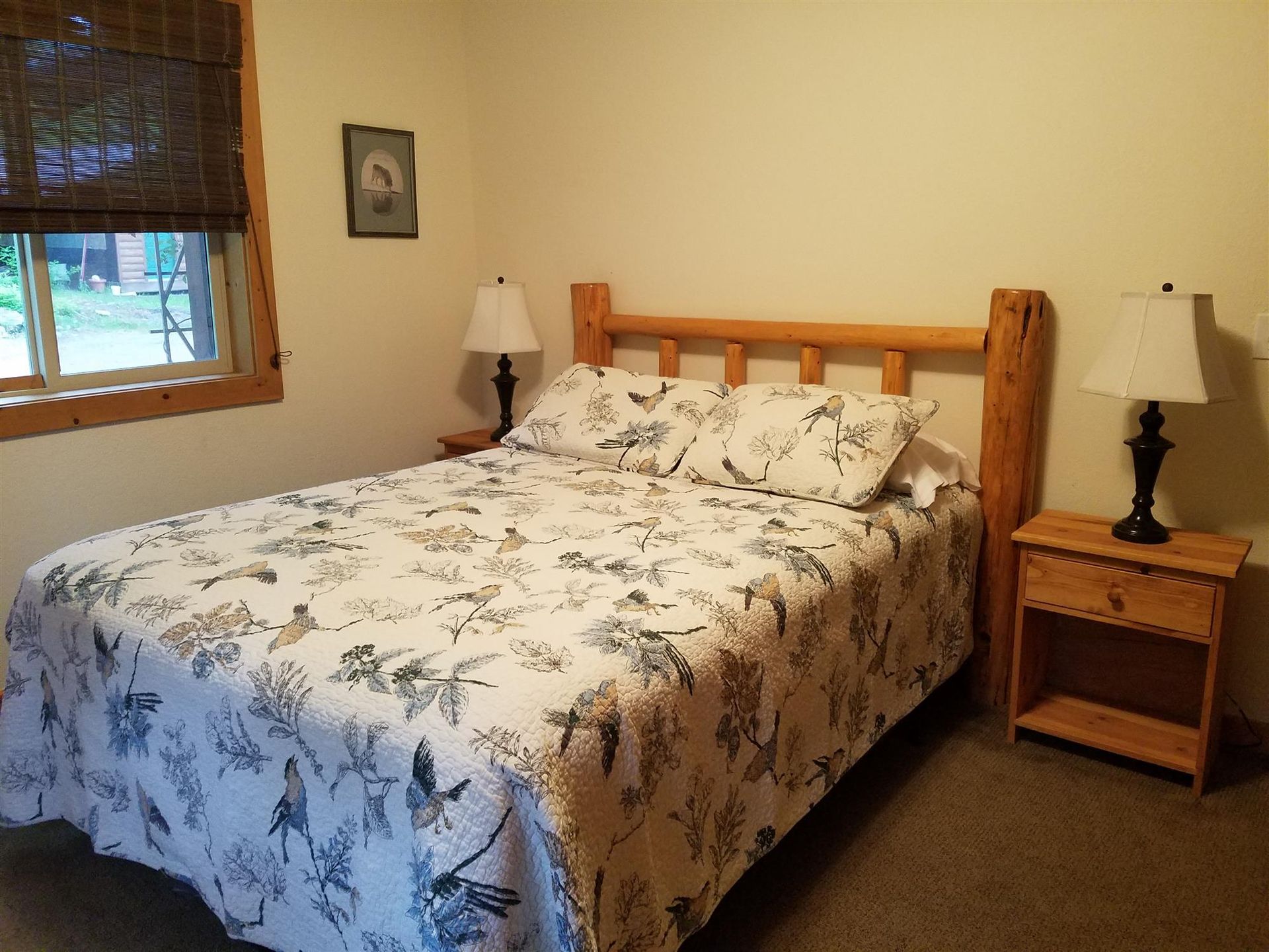 A bedroom with a bed , nightstand , lamp and window