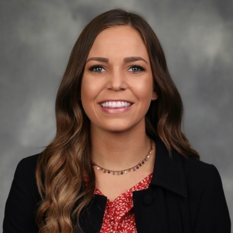 A profile picture of Dr. Hayley Phillips in a black jacket and a red shirt.
