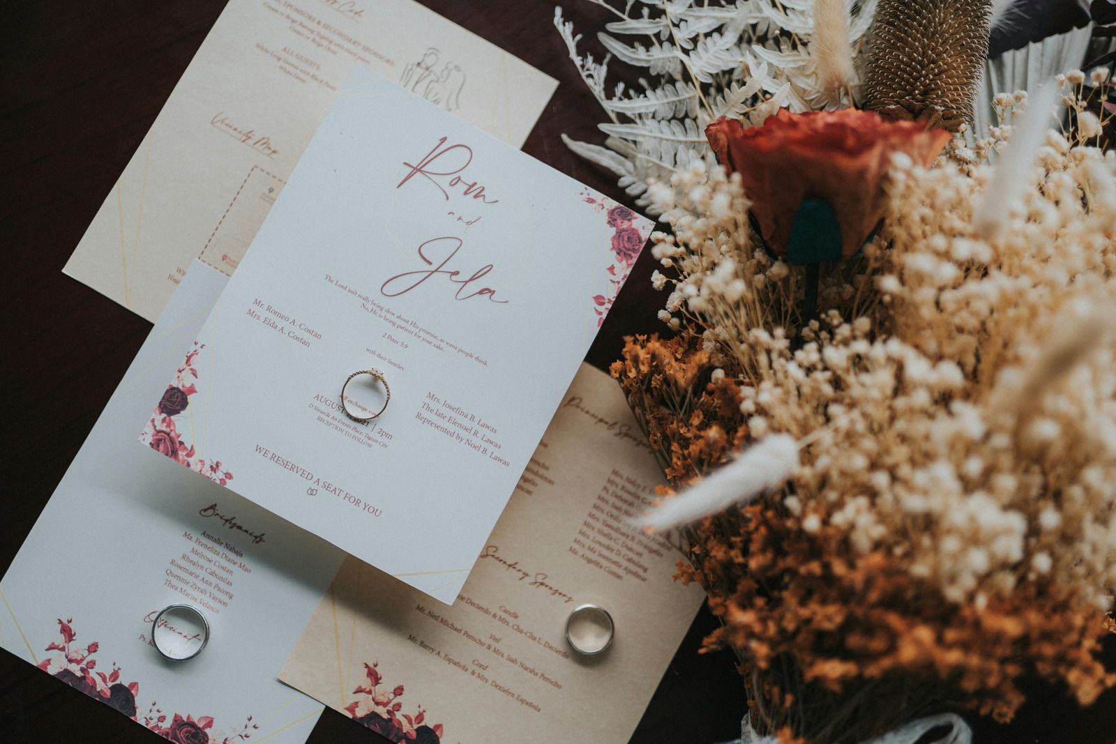 A machine laminates a sheet of wedding invitation cards, with floral designs, inside a print shop.