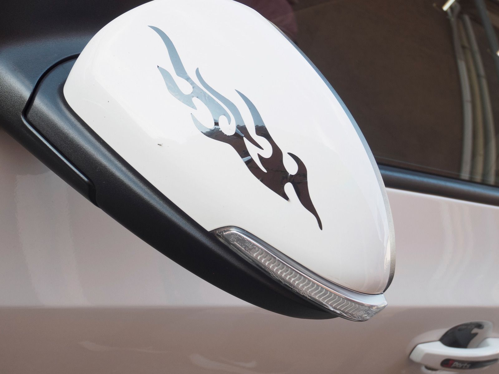 White car side mirror with black flame decal.