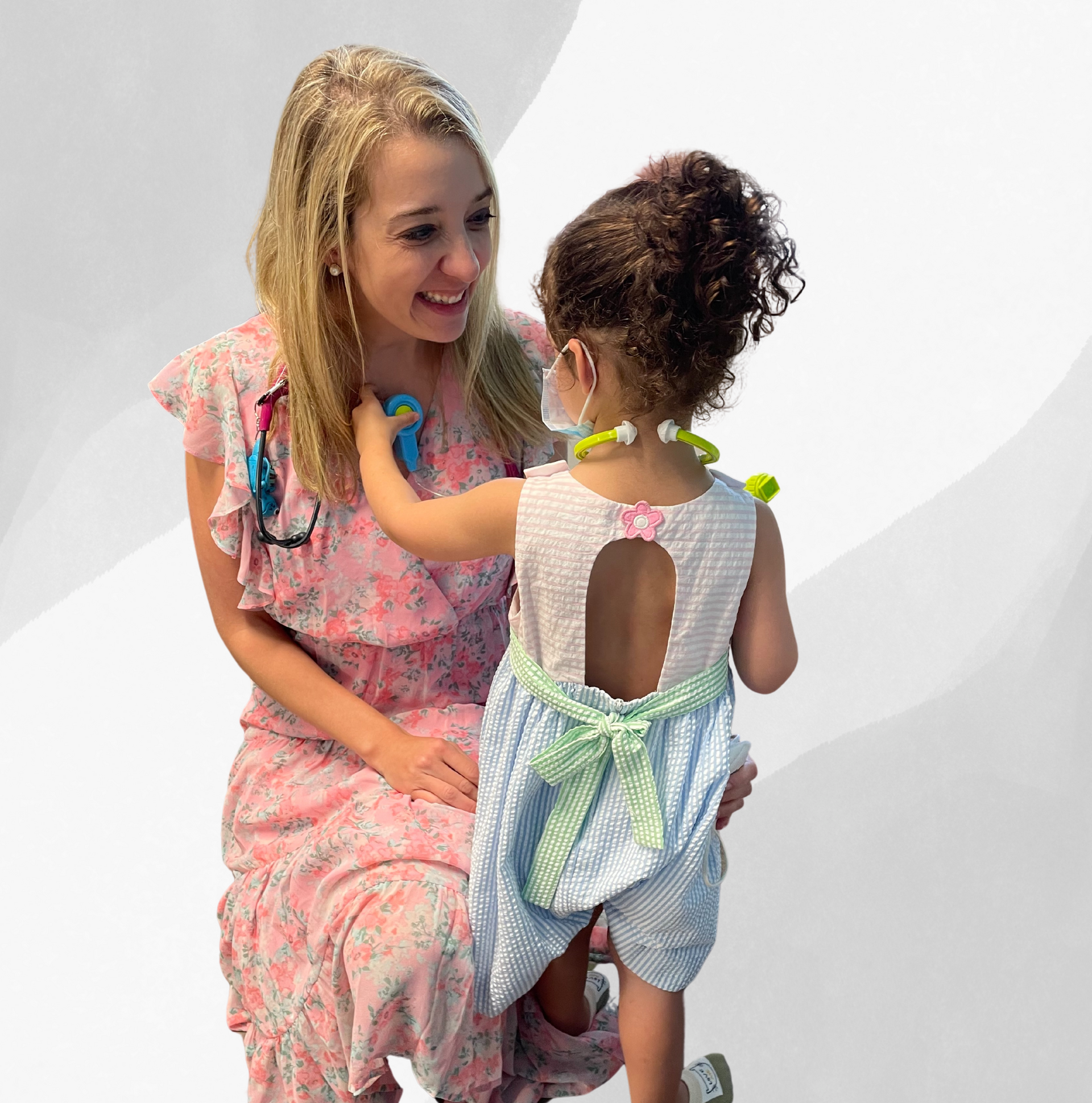 A little girl is playing with a stethoscope on a woman 's neck.