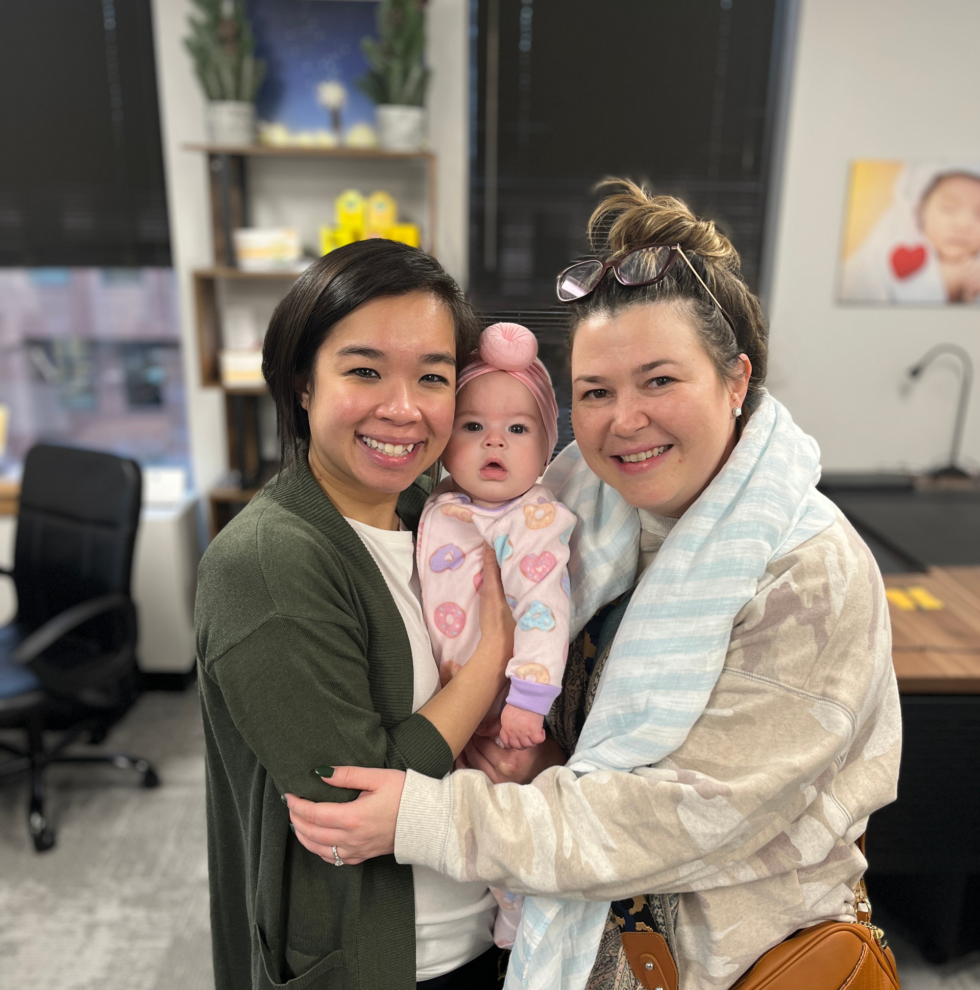 Two woman hugging with a baby cuddled in between them