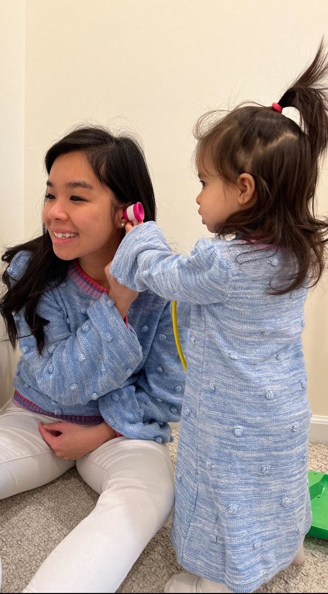 Little girl looking in the ear of a woman