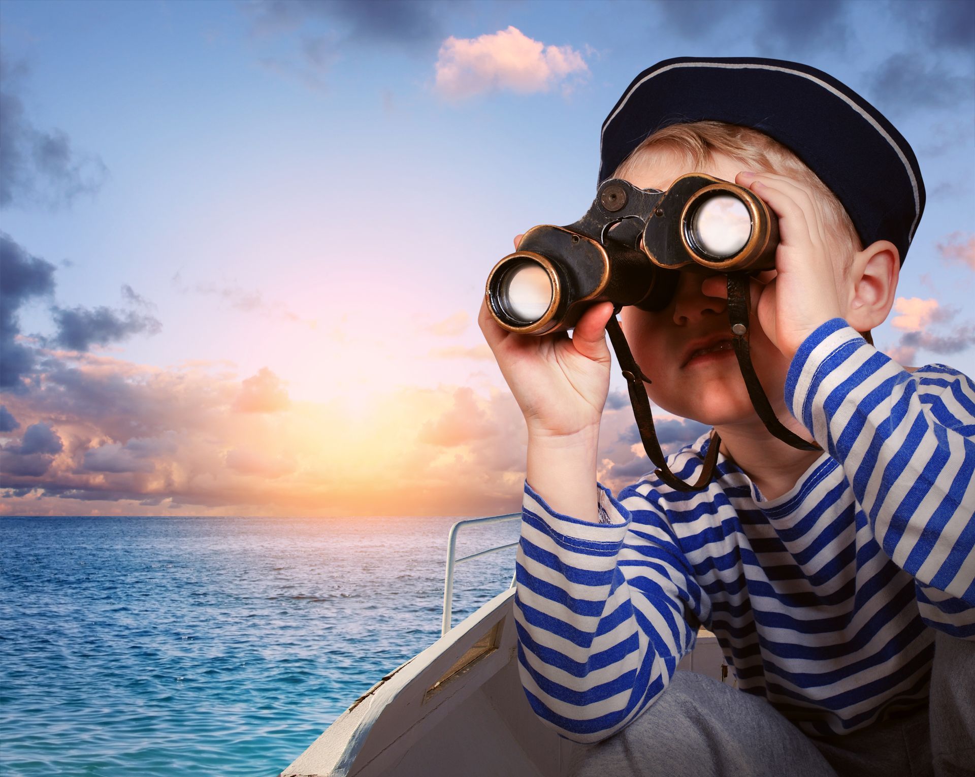 Boy dressed as a sailor with a striped shirt and cap looking through binoculars