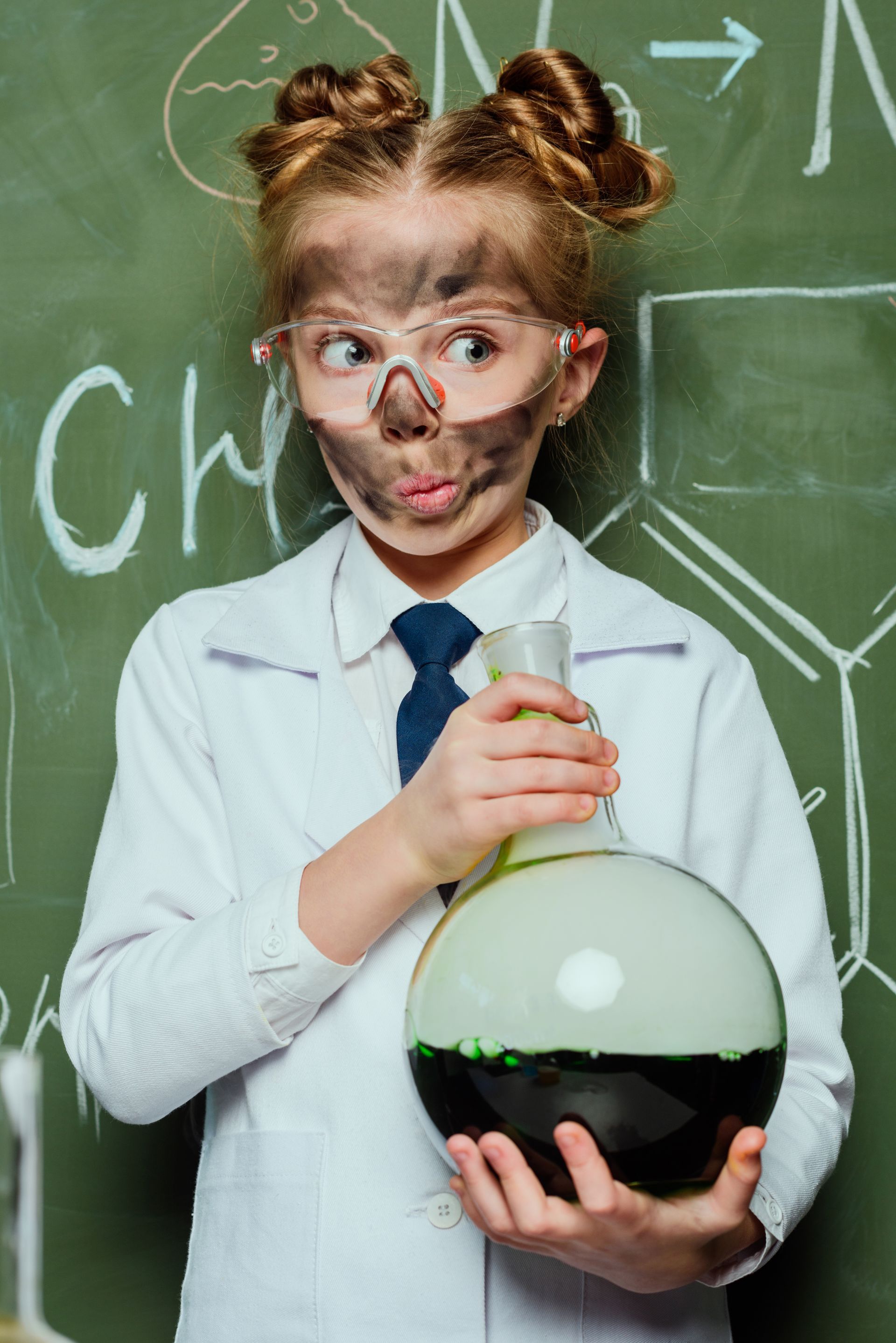 Little boy holding a lab beeker with smoke soot on his face