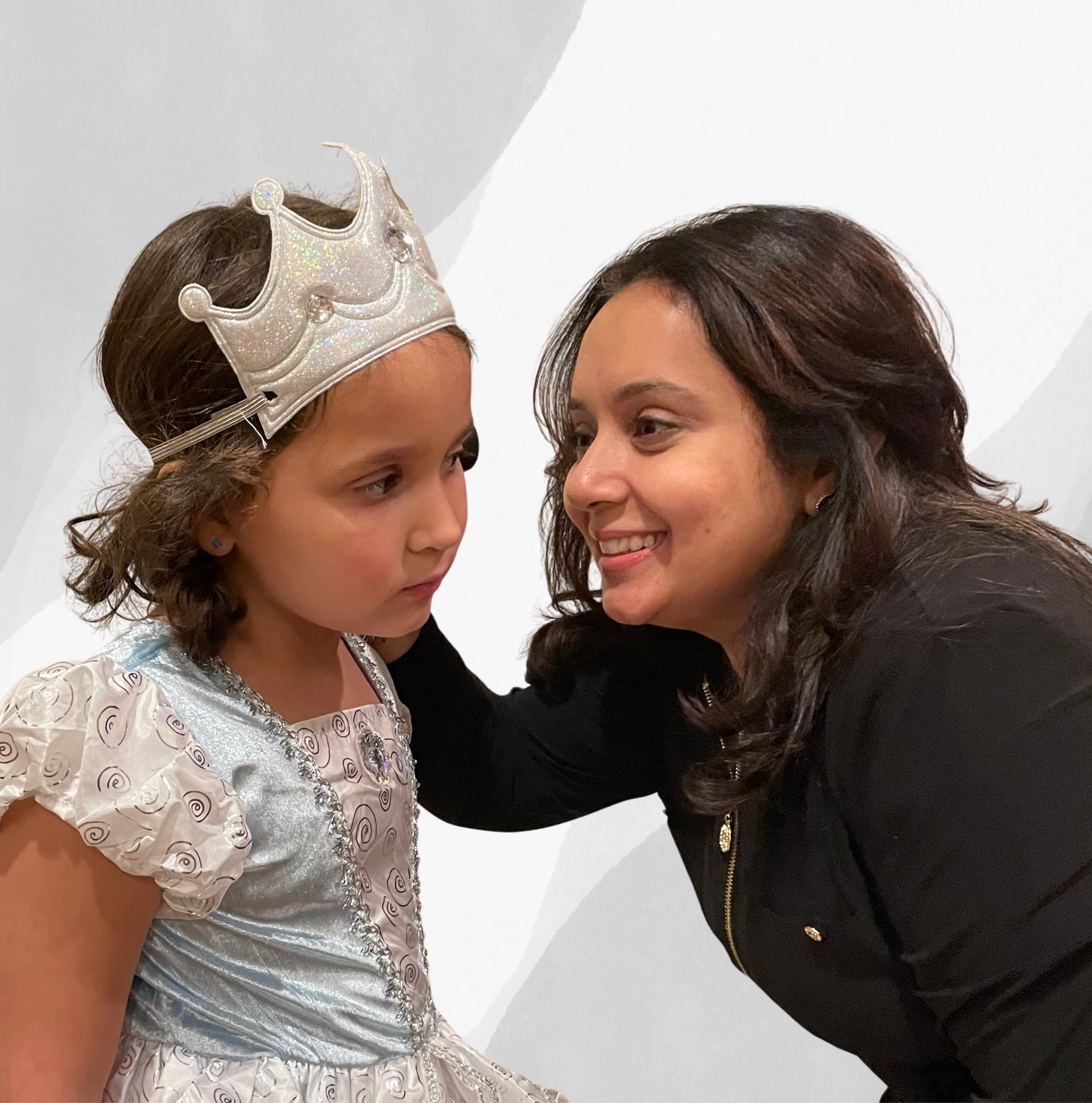 A woman putting a crown on a little girl 's head