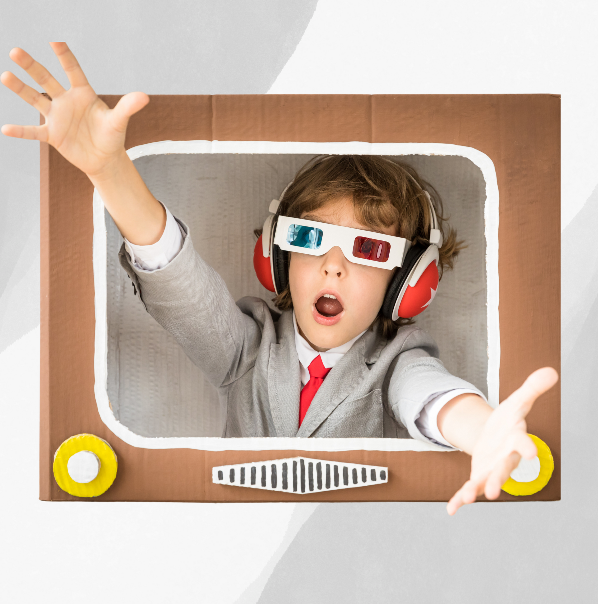 A young boy wearing 3d glasses and headphones is in a cardboard box