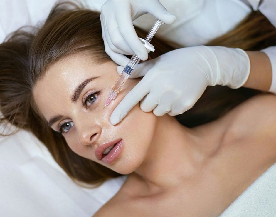 A woman is smiling and touching her face with her hands.