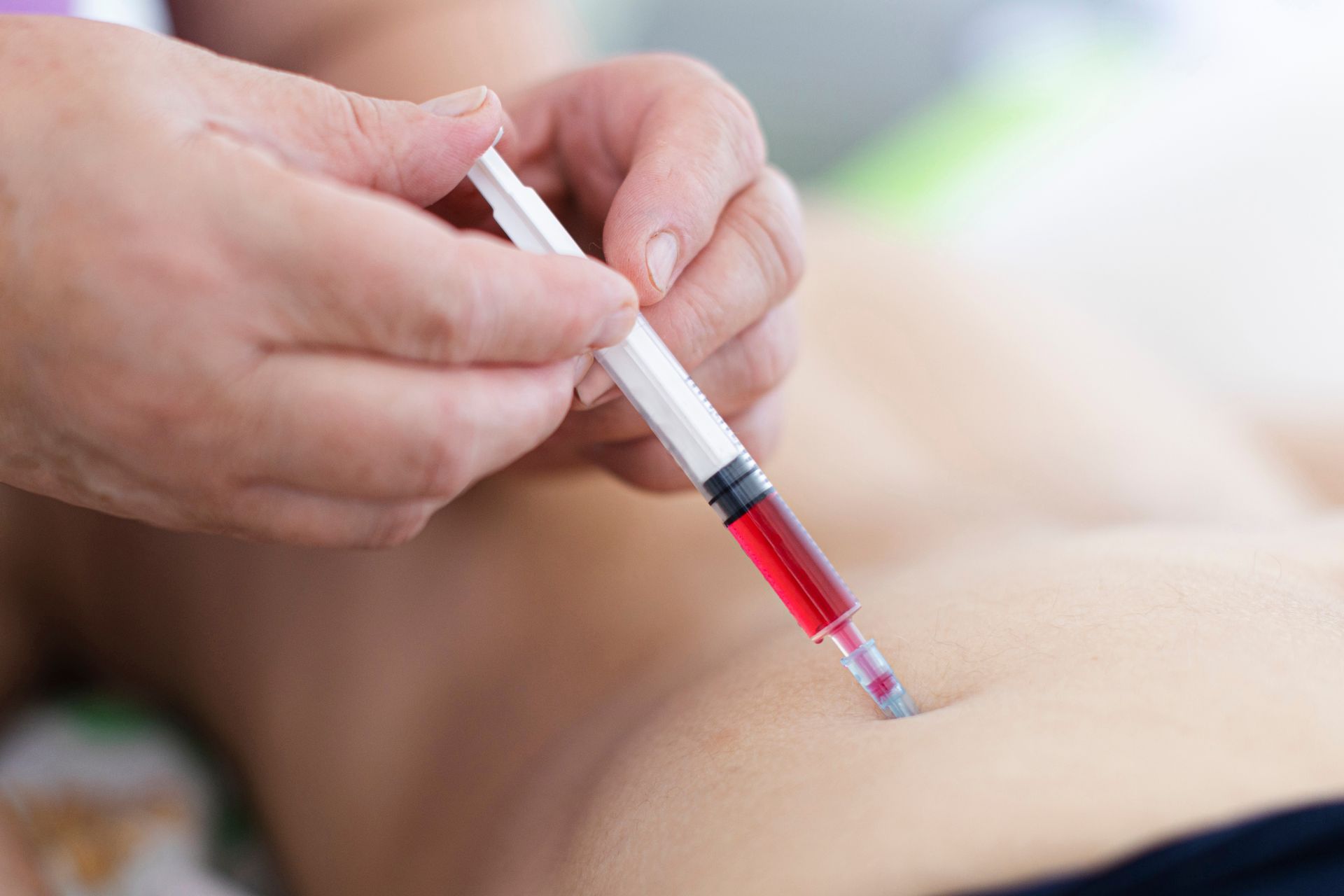 A person is getting an injection in their stomach.