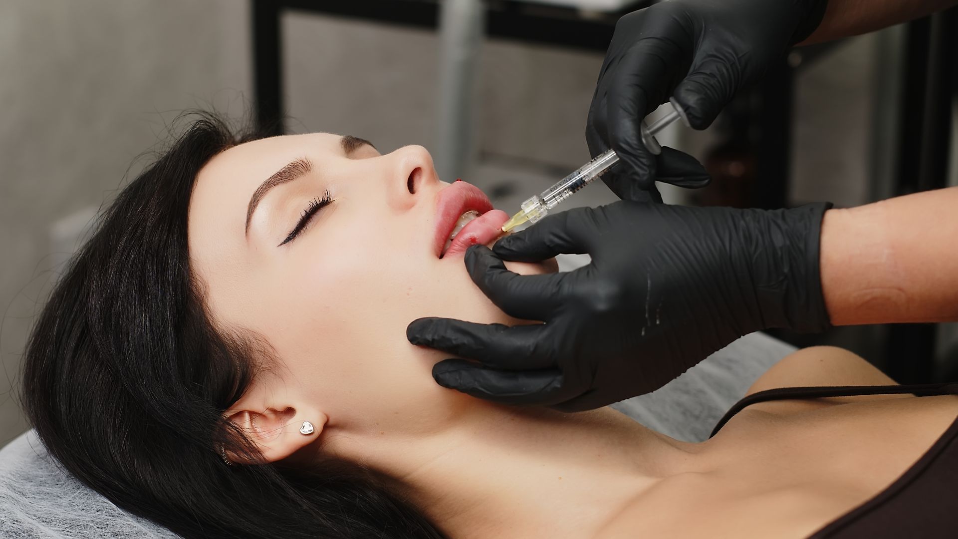 A woman is getting a botox injection in her lips.