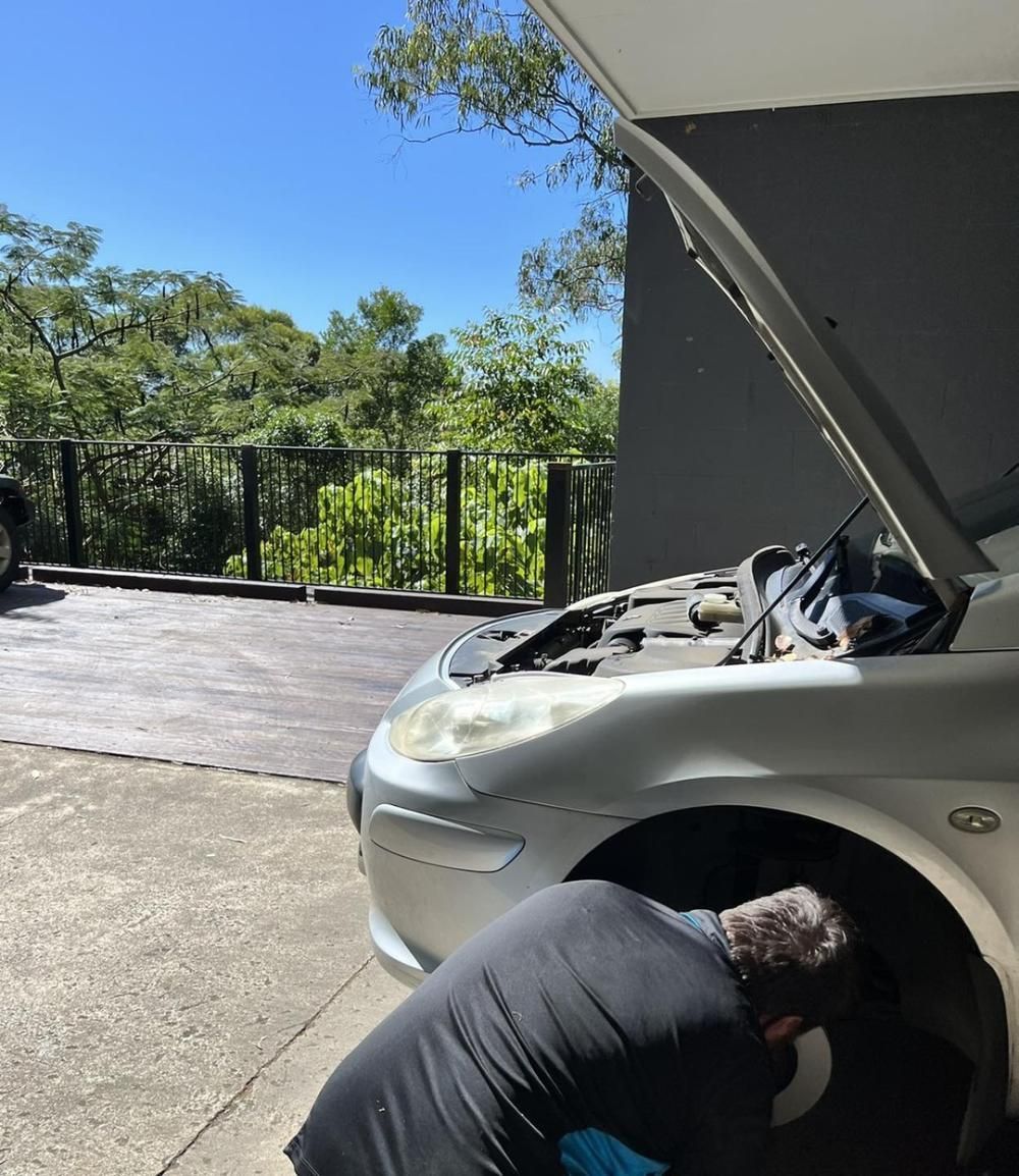 A Man Is Looking Under The Hood Of A Silver Car — Weyba Automotive Services In Kuluin, QLD