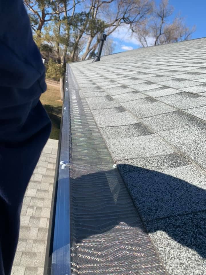 A person is standing next to a gutter on a roof.