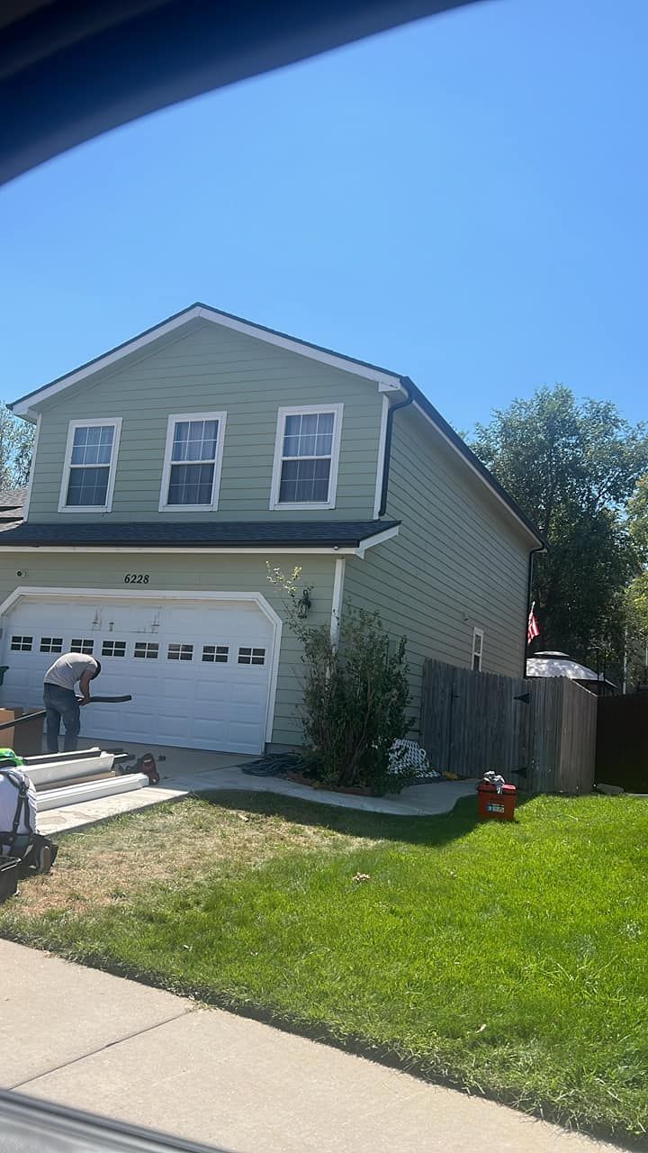 A man is painting a house with a white garage door.