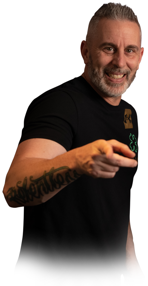 A man with a tattoo on his arm is pointing at the camera.