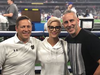 Three people are posing for a picture in a stadium.