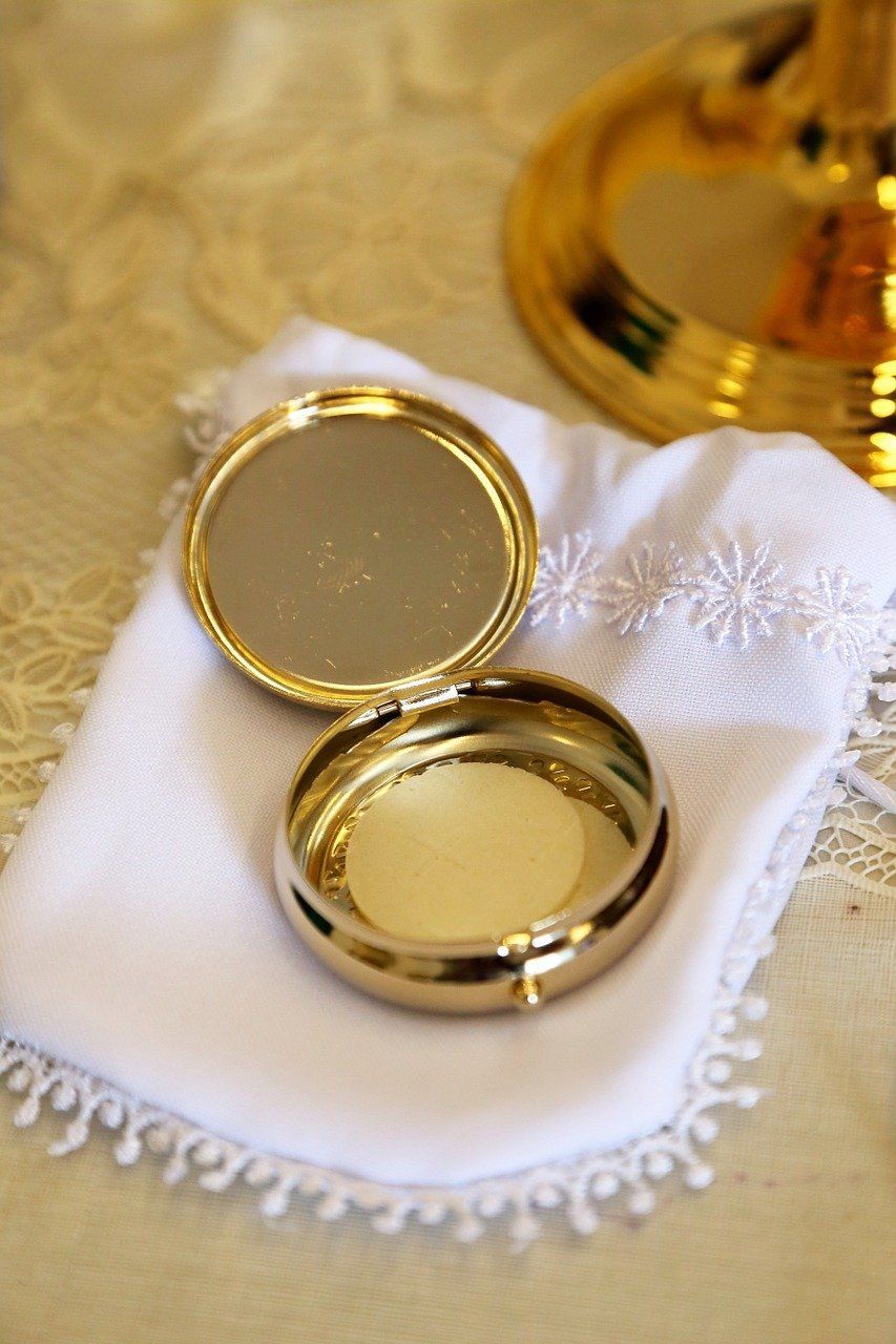 A small gold box is sitting on a white cloth on a table.