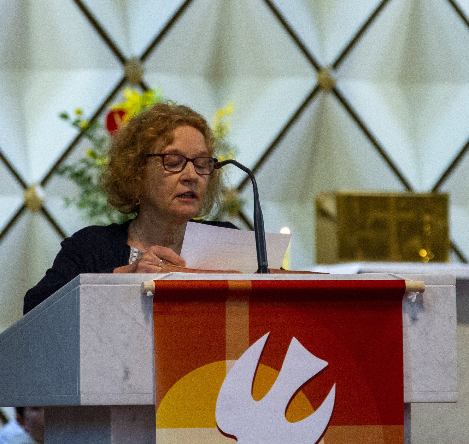 A woman stands behind a podium with a dove on it