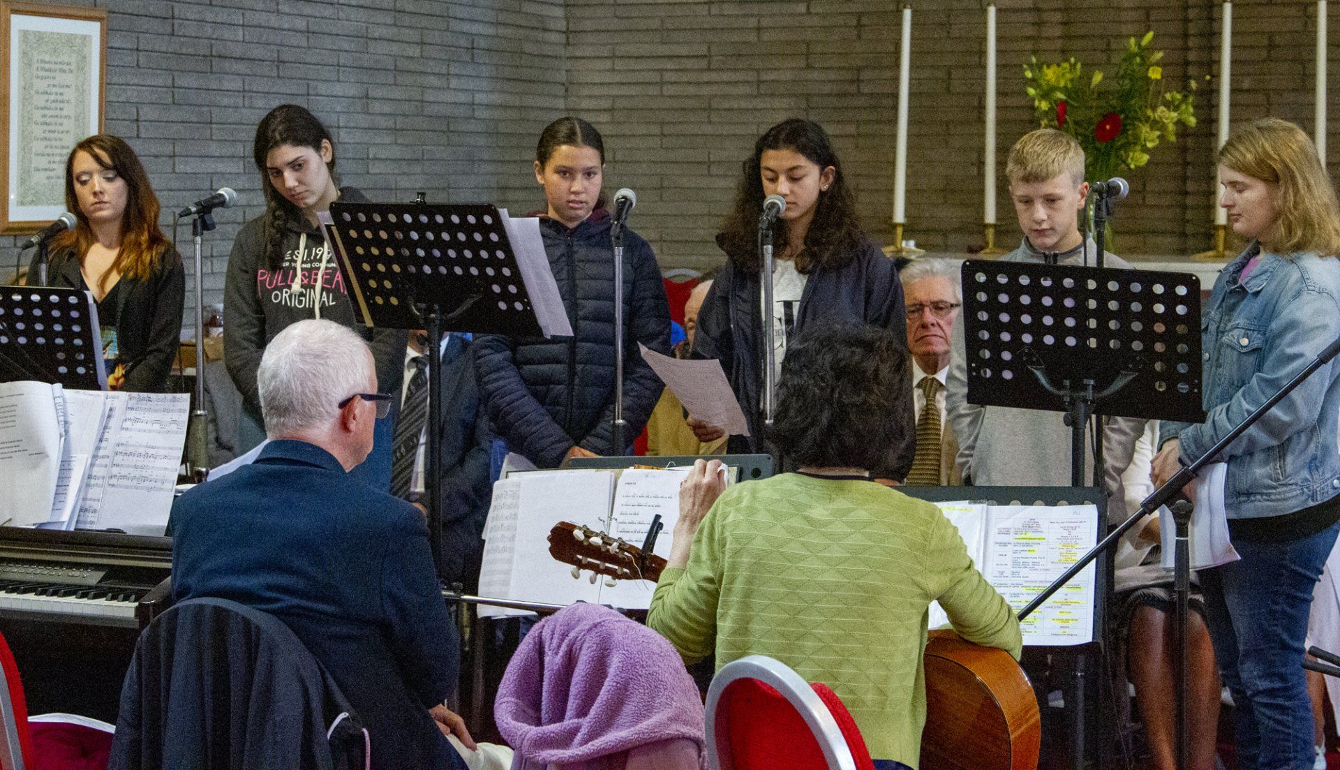 A group of people are standing in front of microphones in a room.