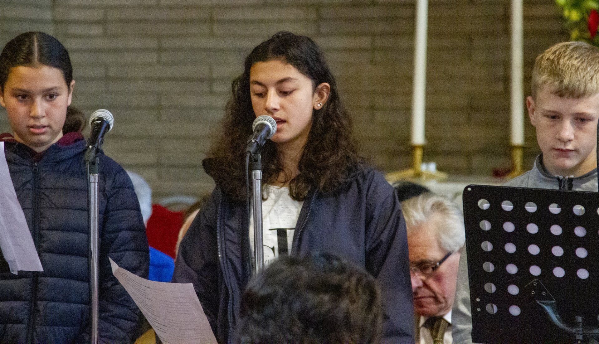 A group of young people are singing into microphones in a church.