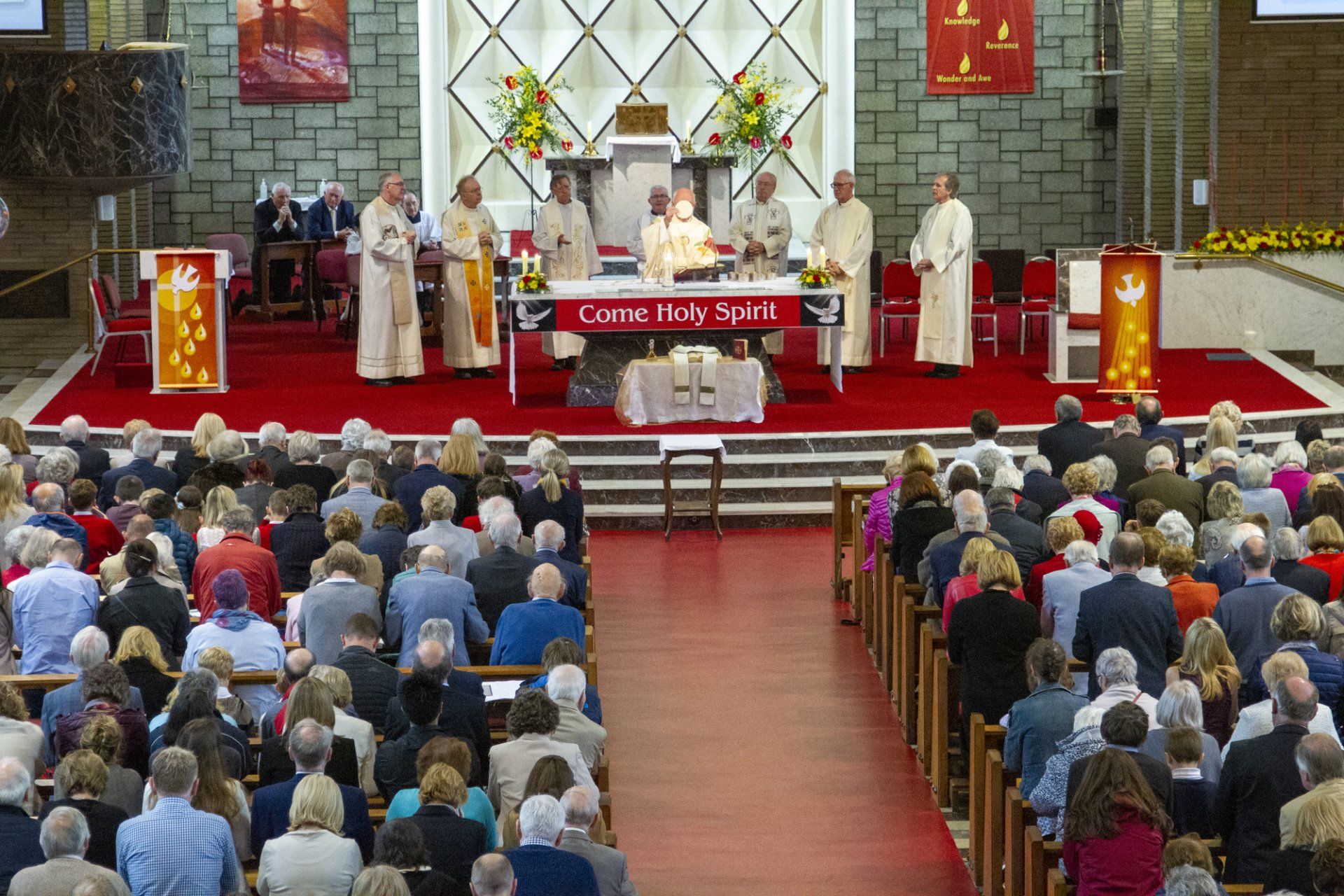 A large group of people are sitting in a church watching a service.