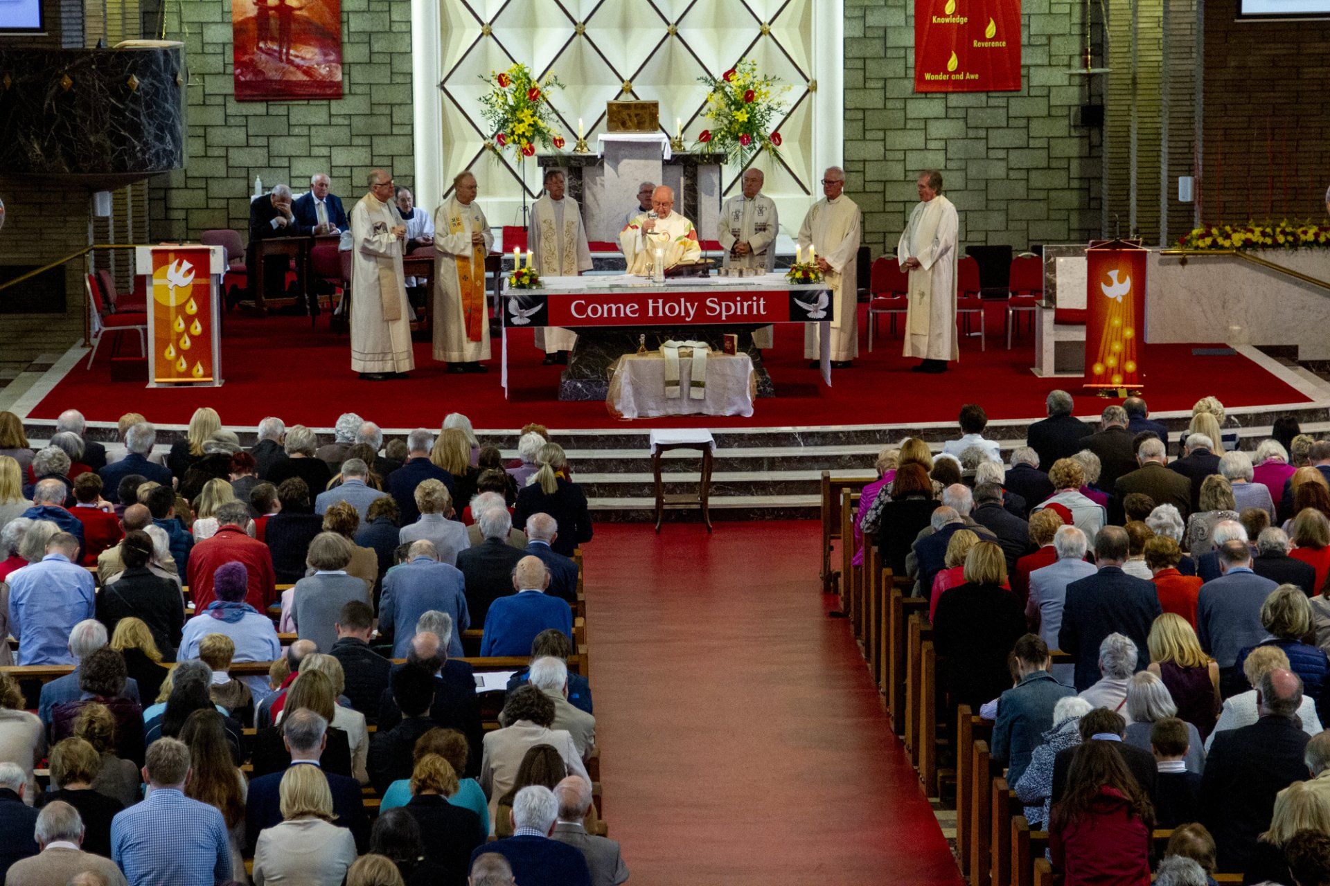 A large group of people are sitting in a church watching a mass