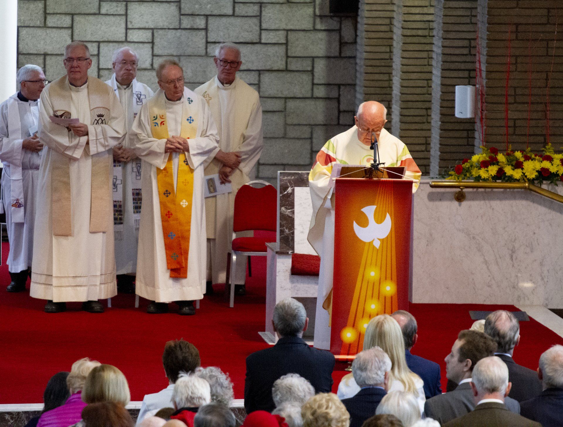 A group of priests are standing around a podium with a dove on it