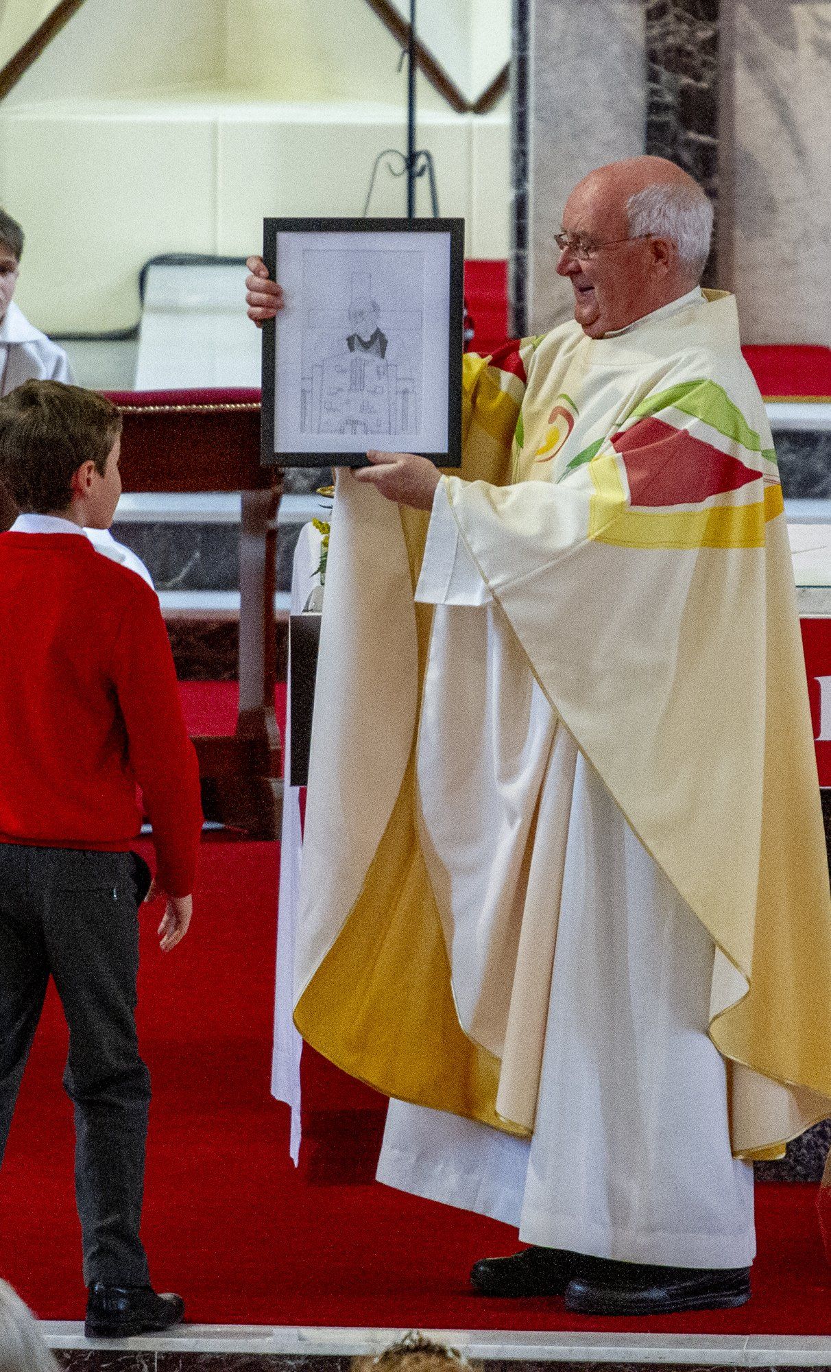 A man in a white robe is holding a framed picture of jesus.