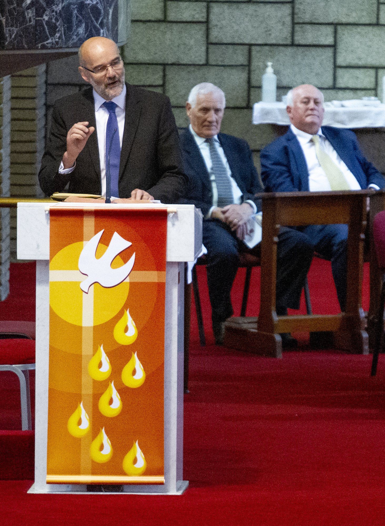 A man stands behind a podium with a dove on it