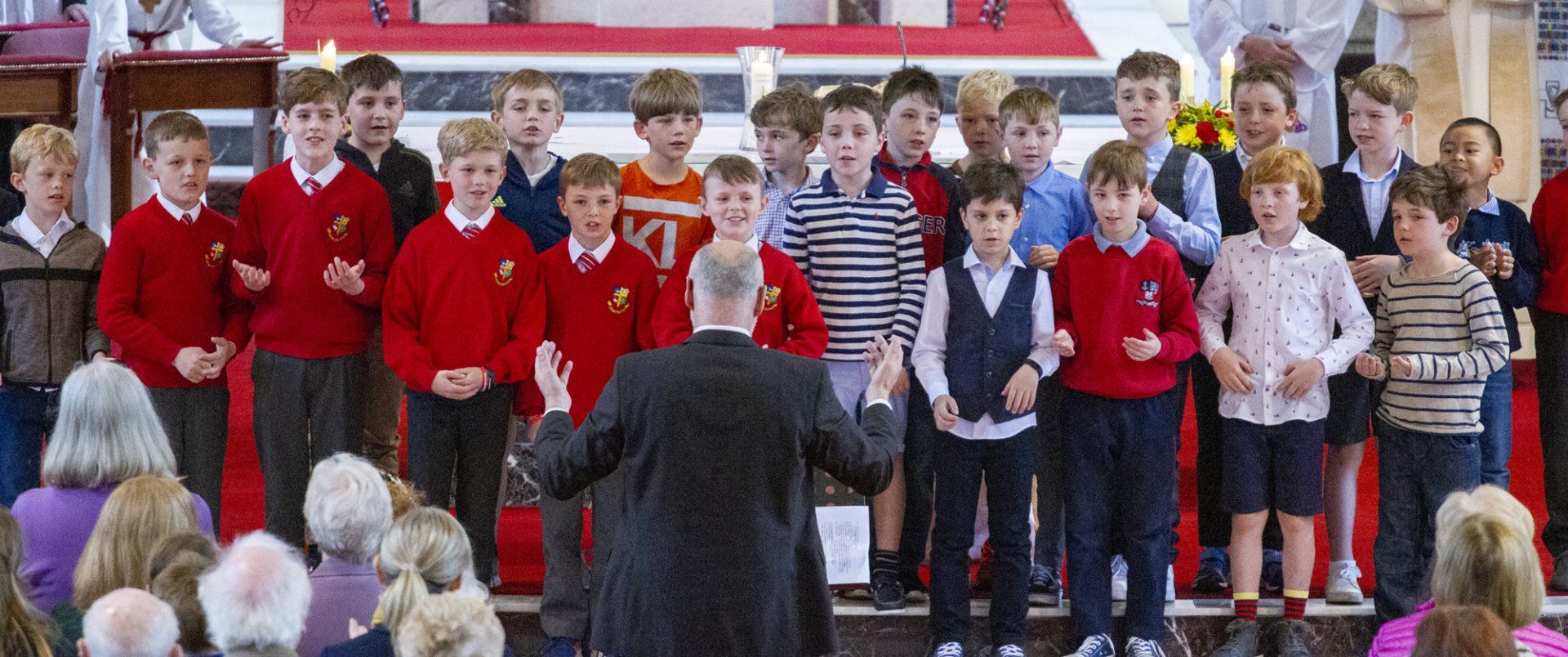 A man is leading a choir of children in a church.