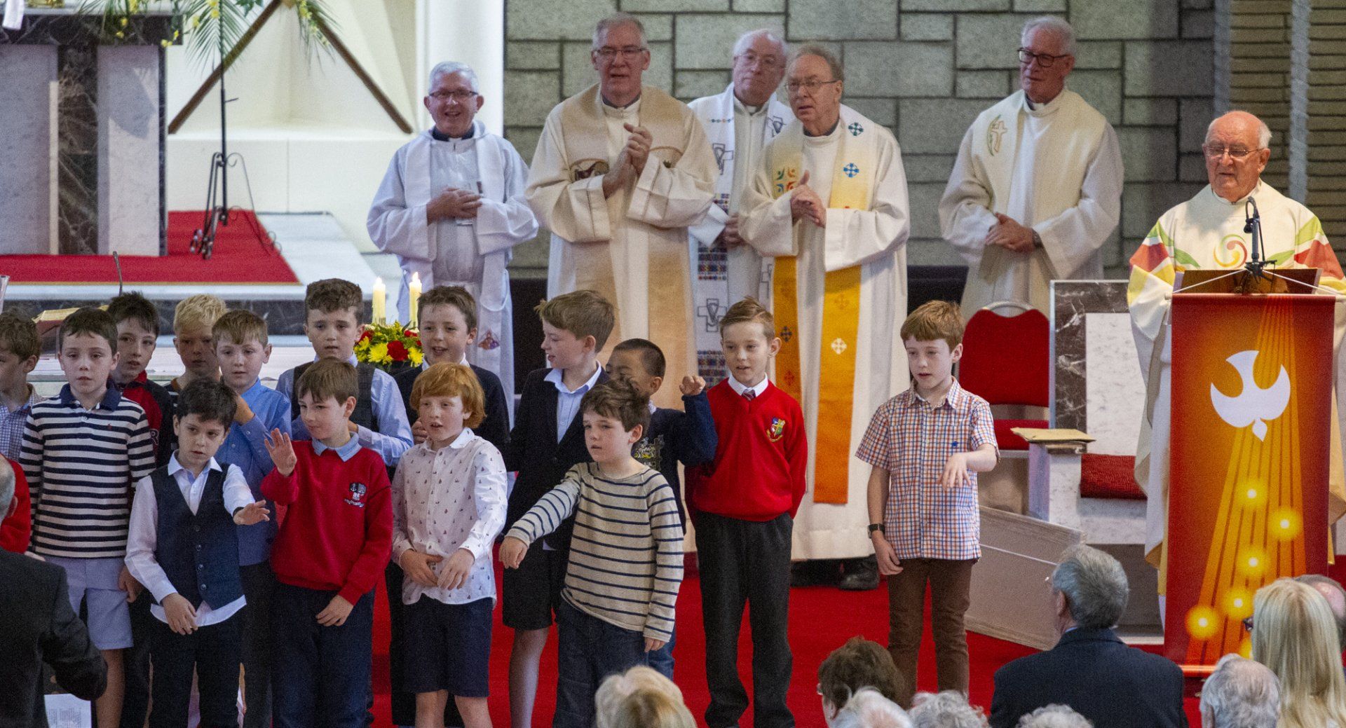 A group of children are standing in front of a podium in a church.