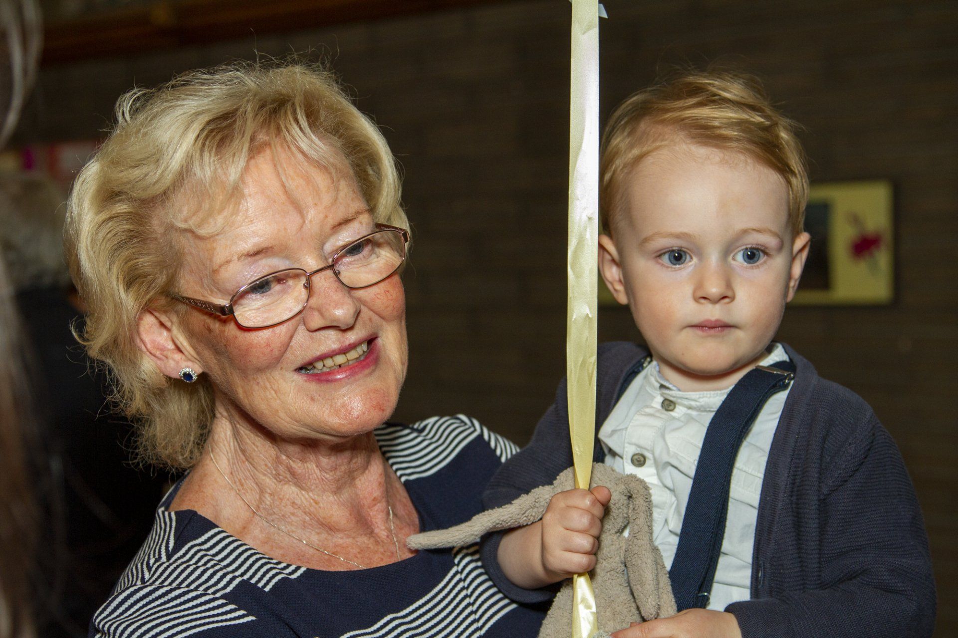 An elderly woman is holding a baby in her arms.