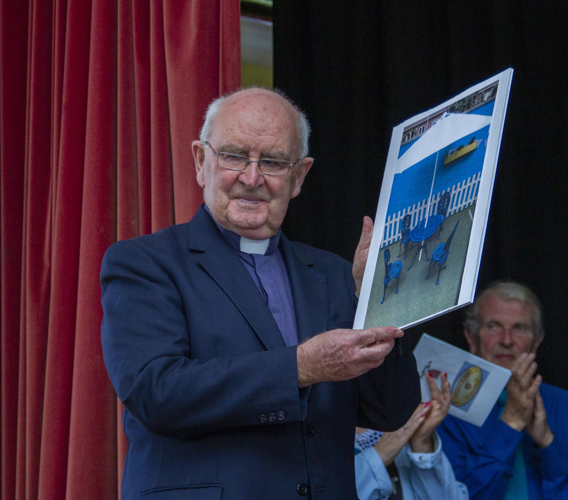 A man in a suit is holding a picture of a fence