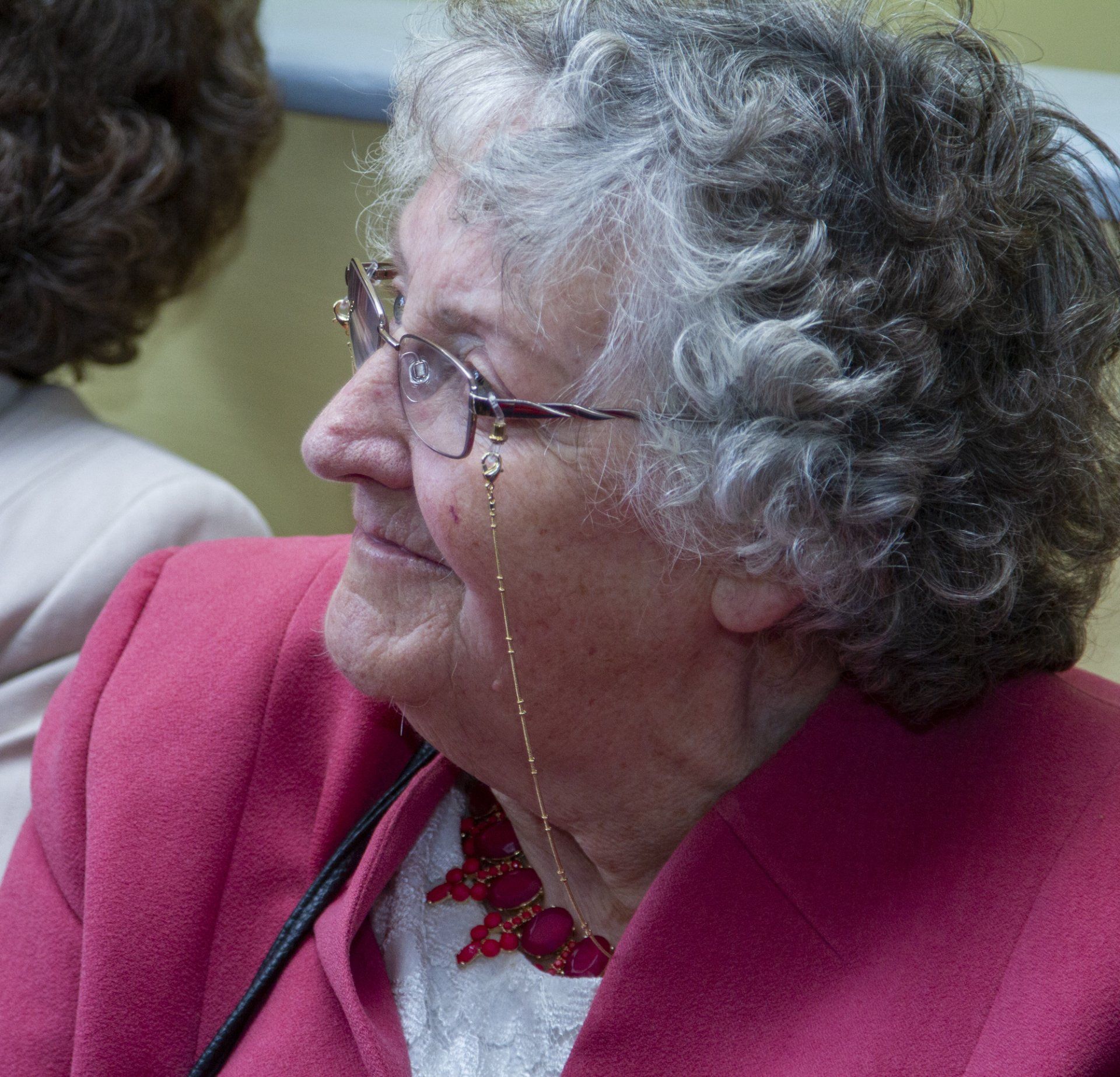 An older woman wearing glasses and a pink jacket