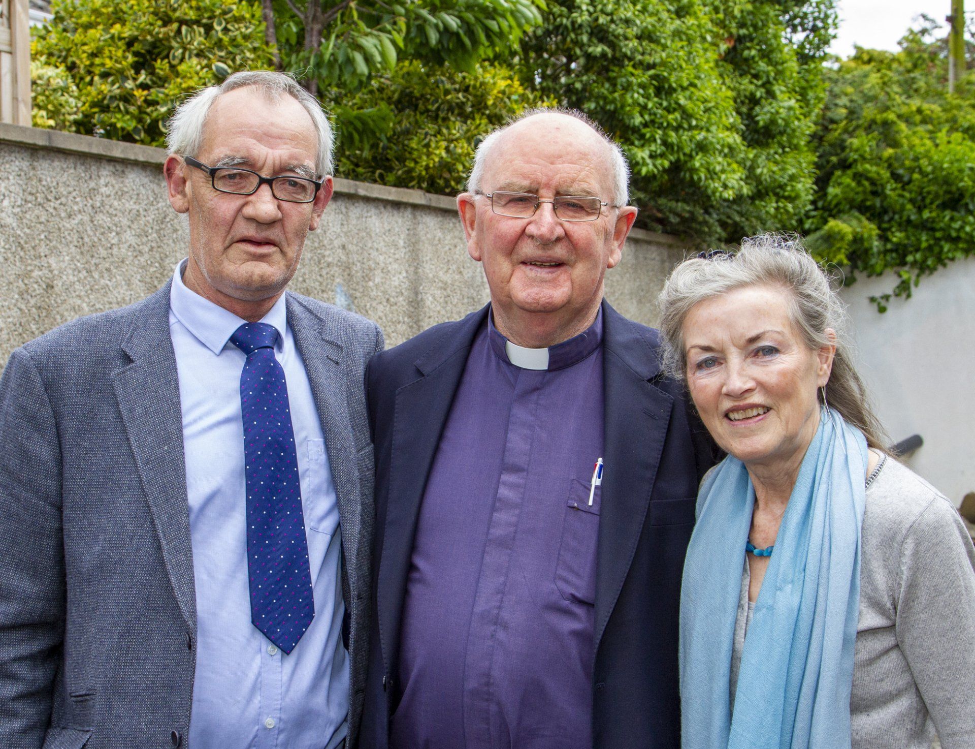 Two men and a woman are posing for a picture together.