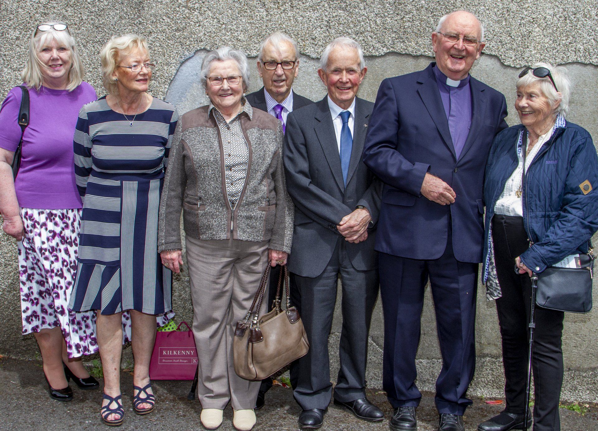 A group of people standing next to each other in front of a wall.