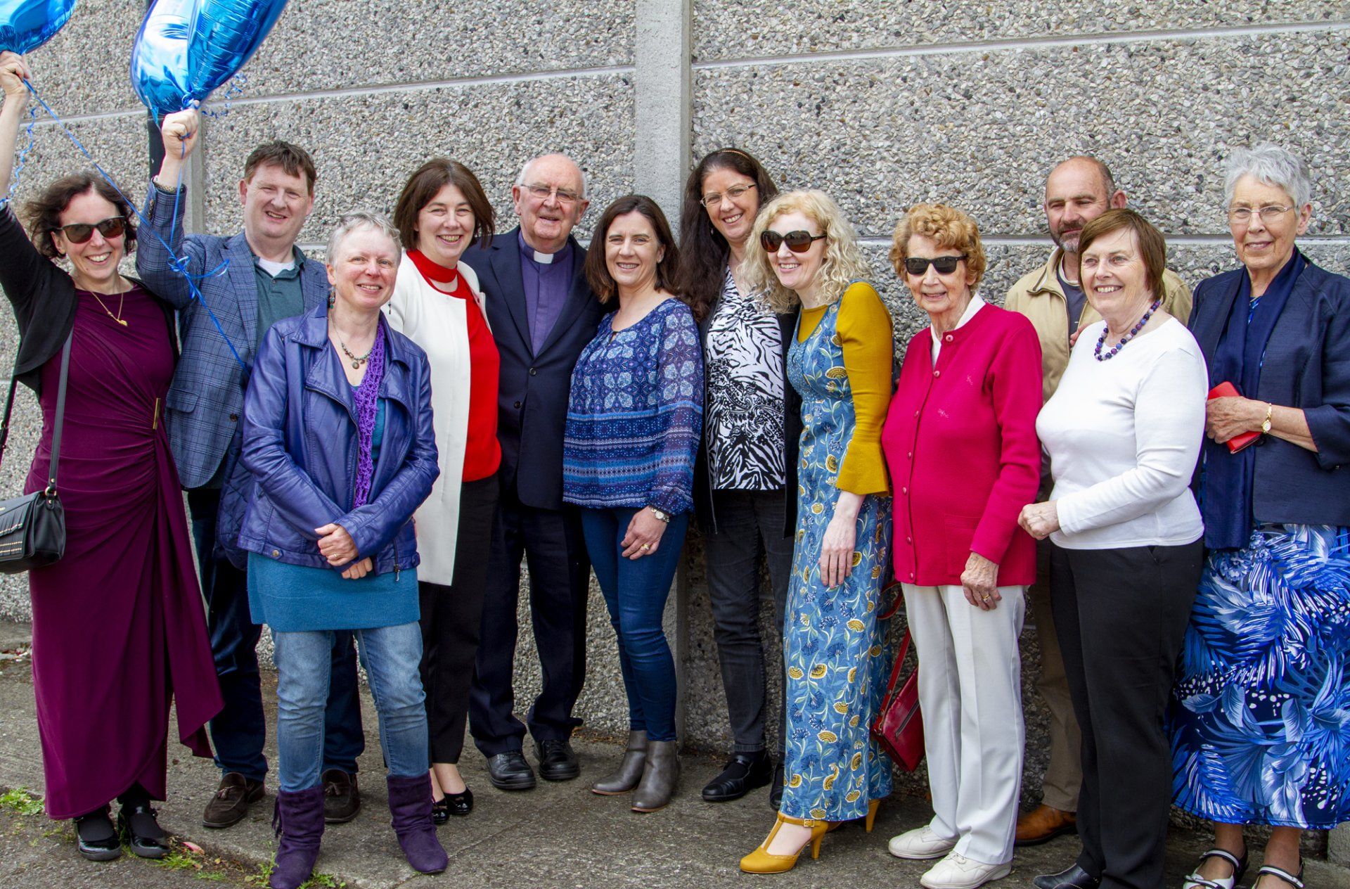 A group of people are posing for a picture in front of a wall.