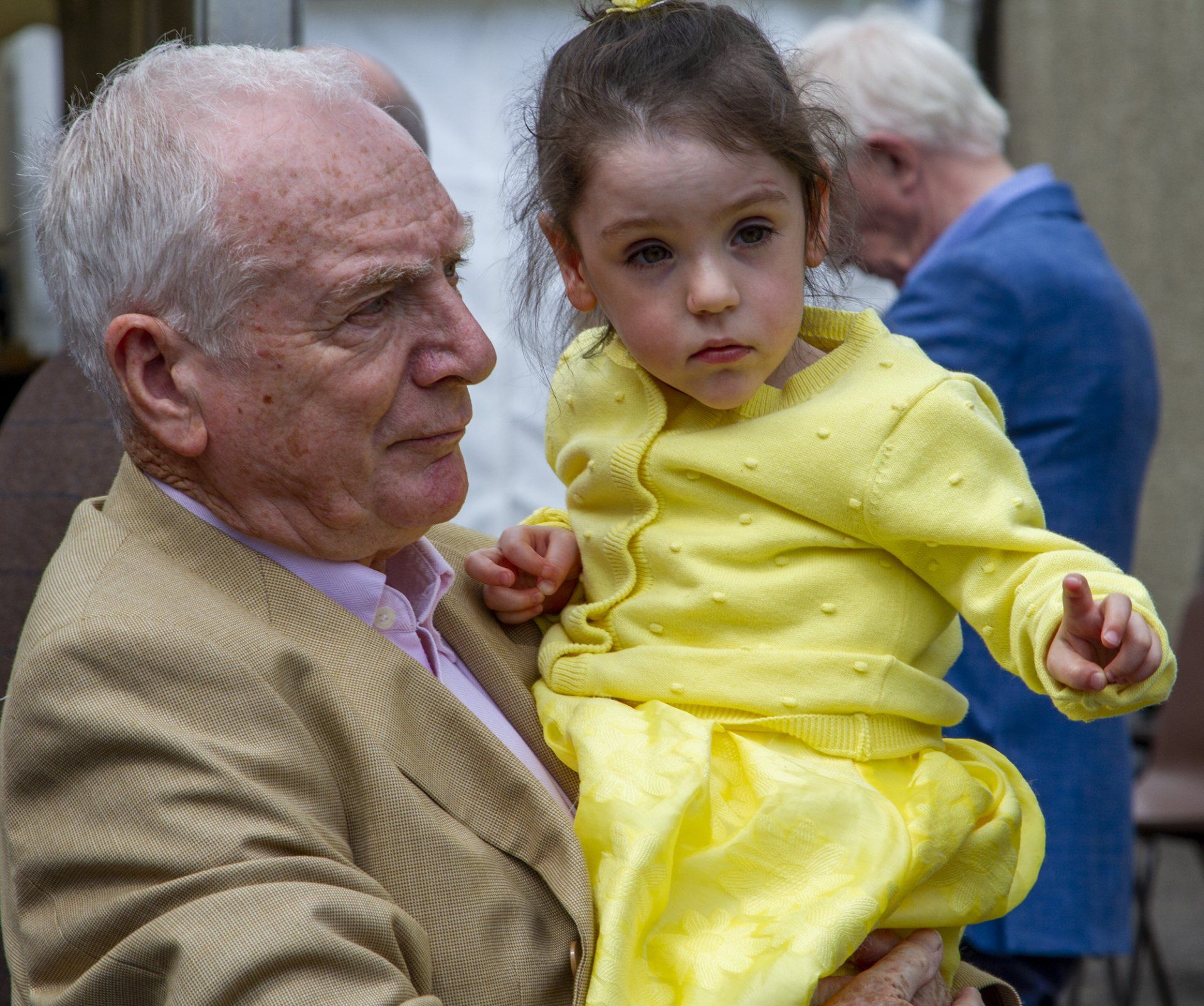 A man is holding a little girl in a yellow dress