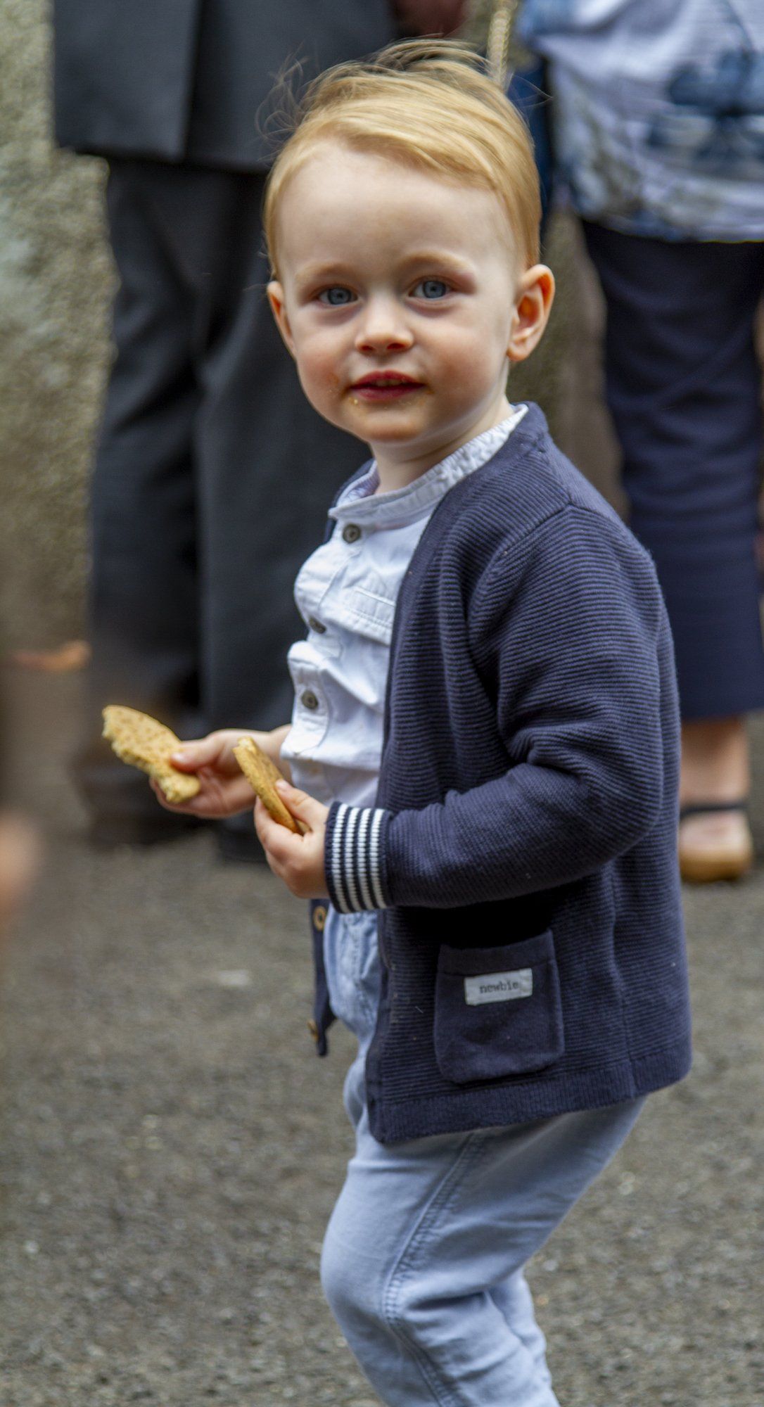 A little boy is holding a piece of food in his hand.