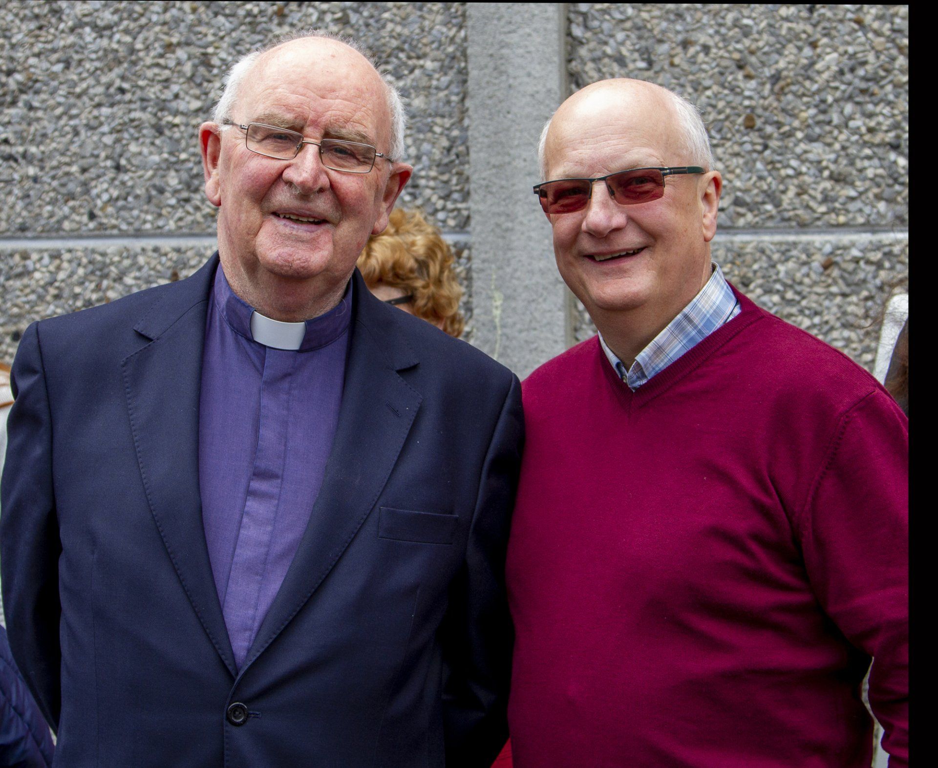Two men are posing for a picture and one is wearing glasses
