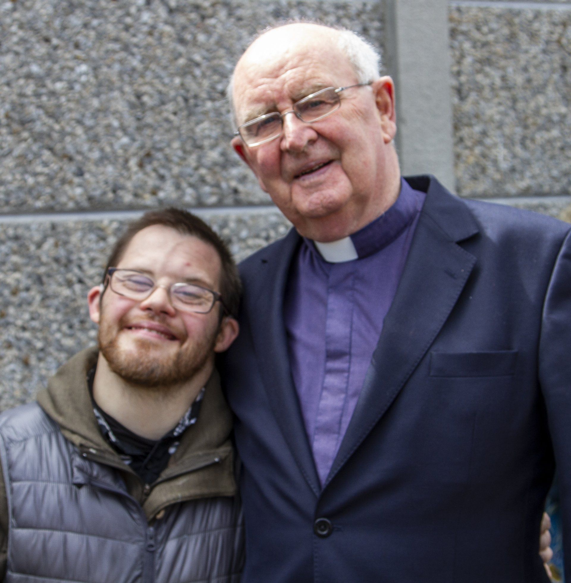 Two men posing for a picture with one wearing glasses