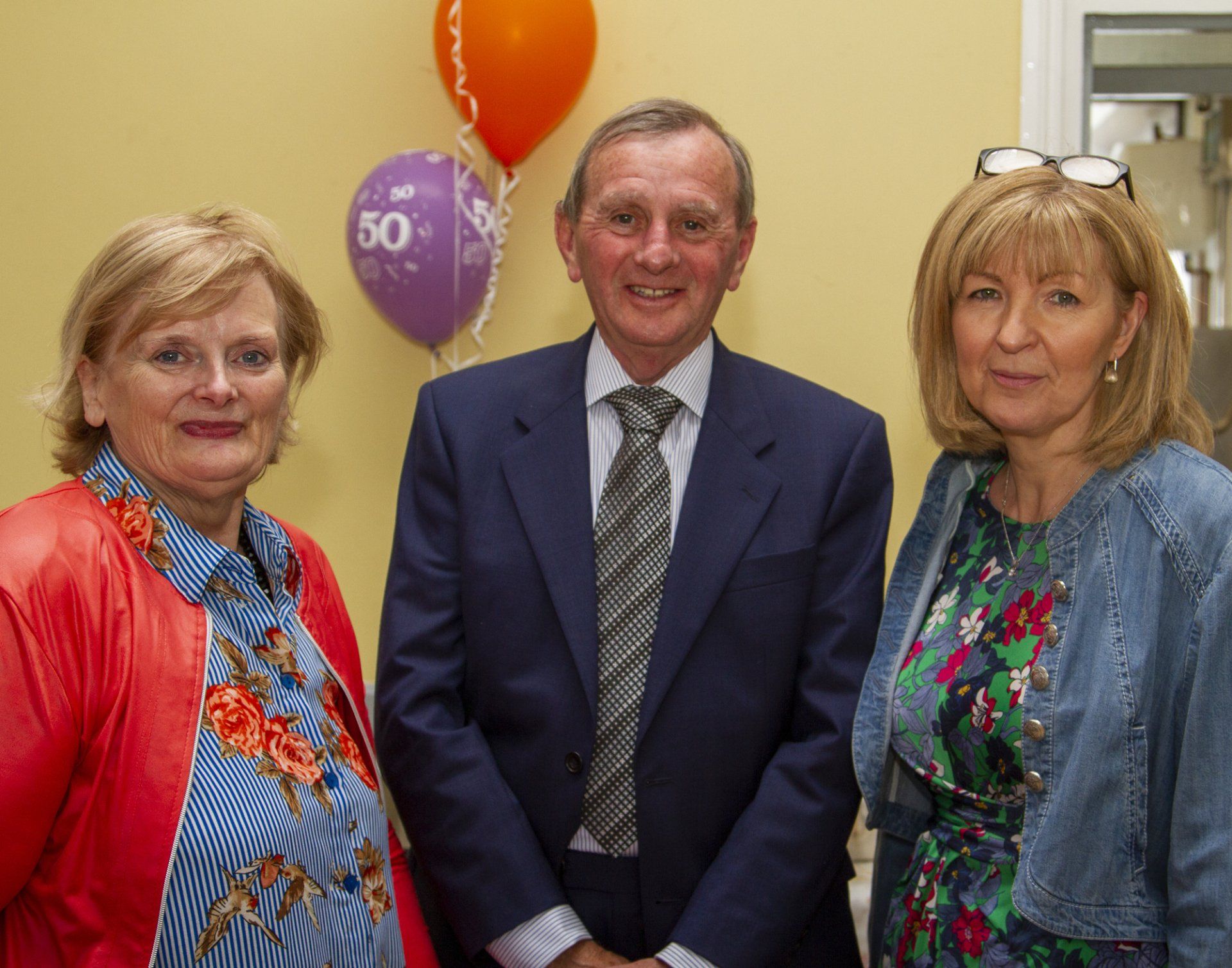 A man in a suit and tie is standing next to two women.