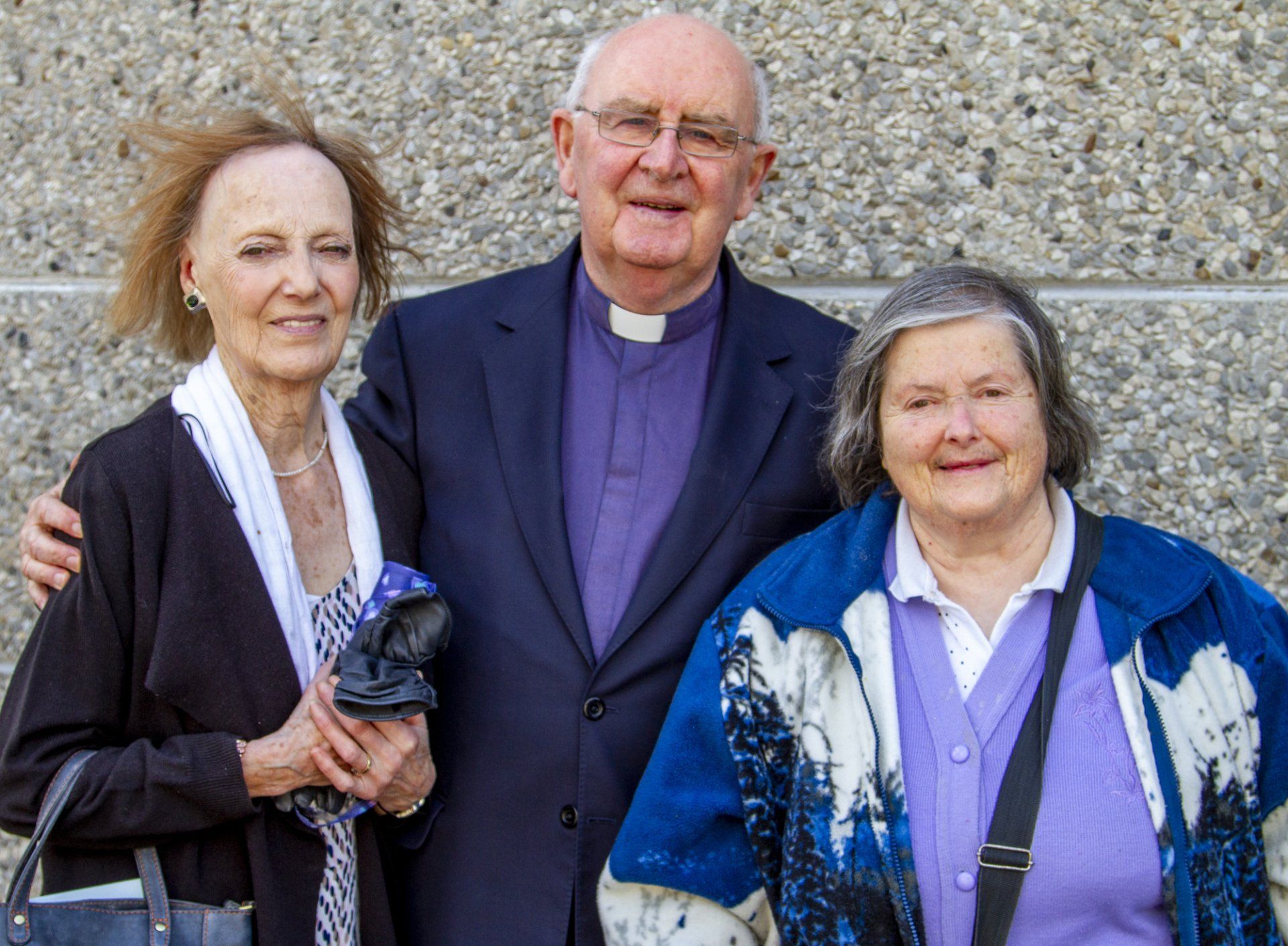 A man in a purple suit is posing for a picture with two women.