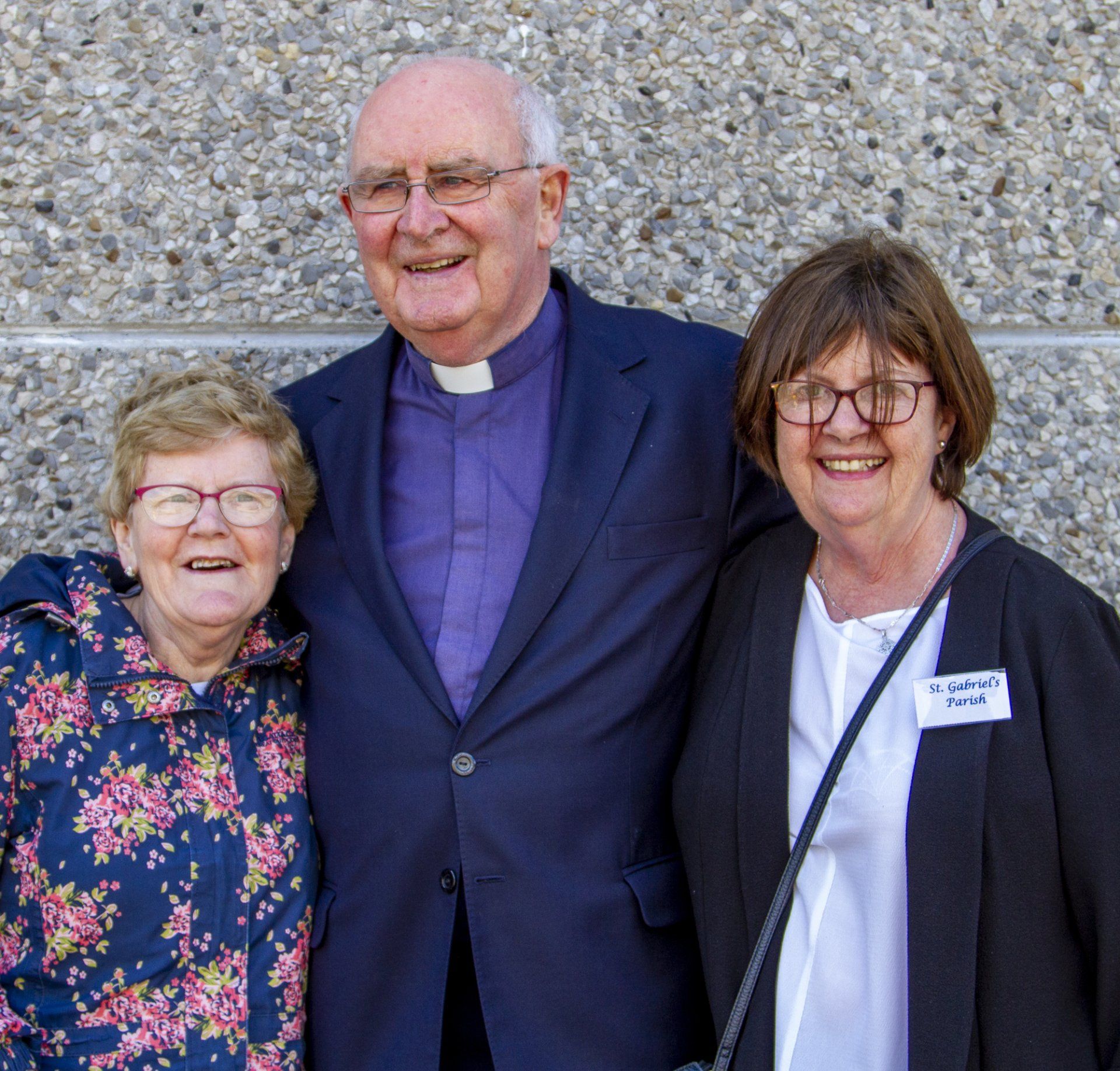 A man in a purple vest is posing for a picture with two women