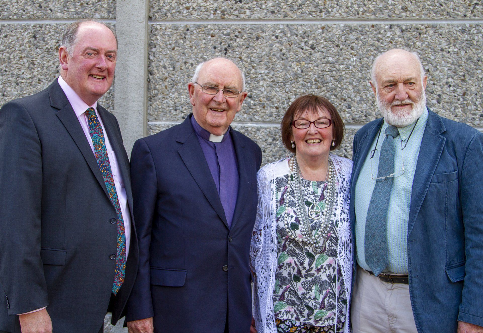 Three men and a woman are posing for a picture together.
