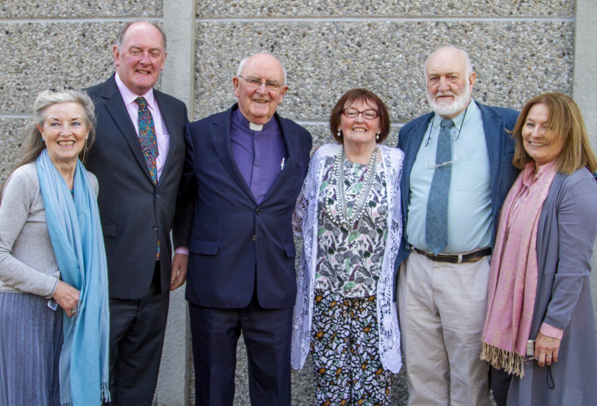 A group of people are posing for a picture in front of a wall.